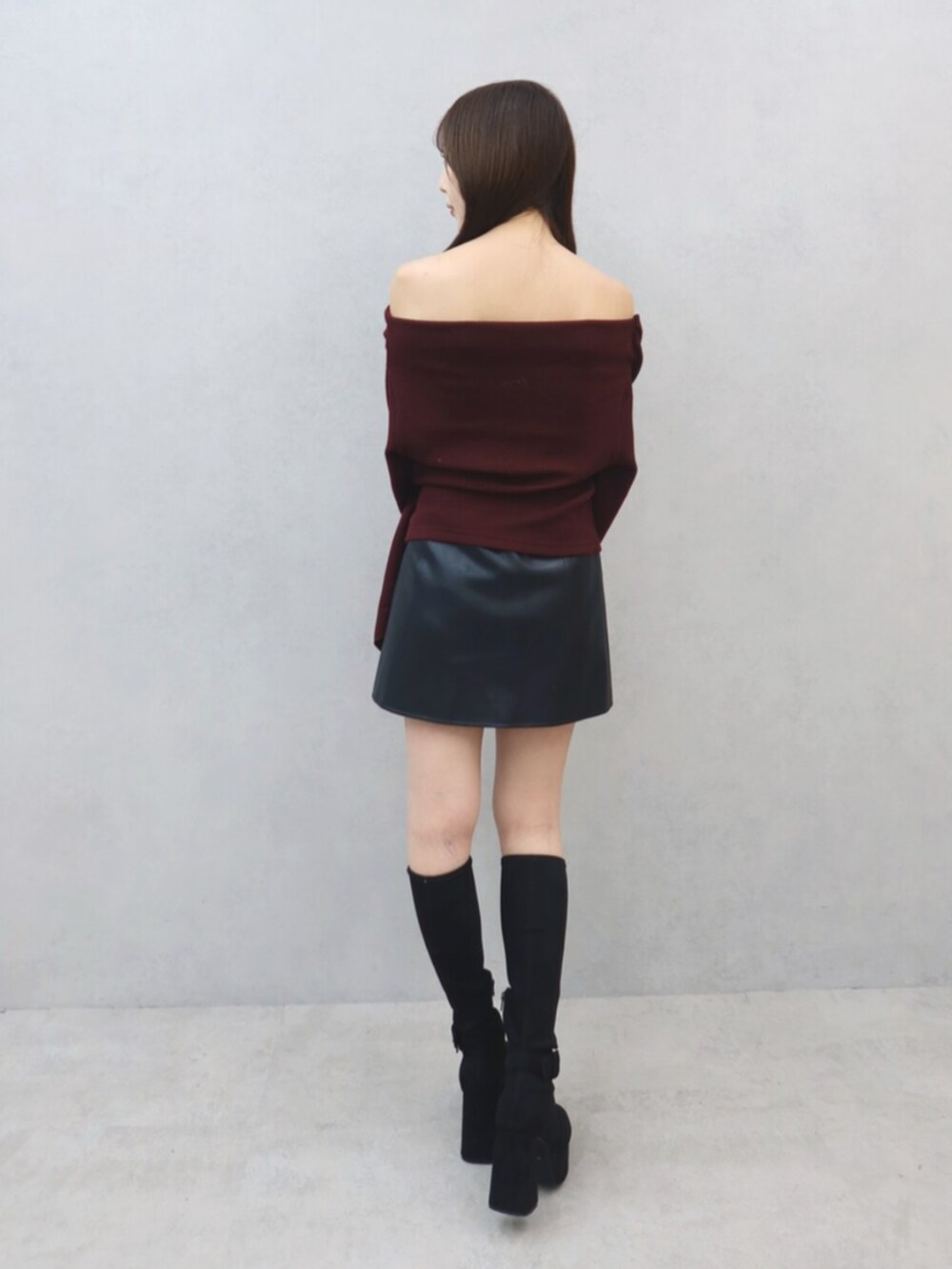 レッド系のTシャツ/カットソー、ブラック系のスカート、ブラック系のブーツを着用したレディースの秋コーディネートの4枚目の写真