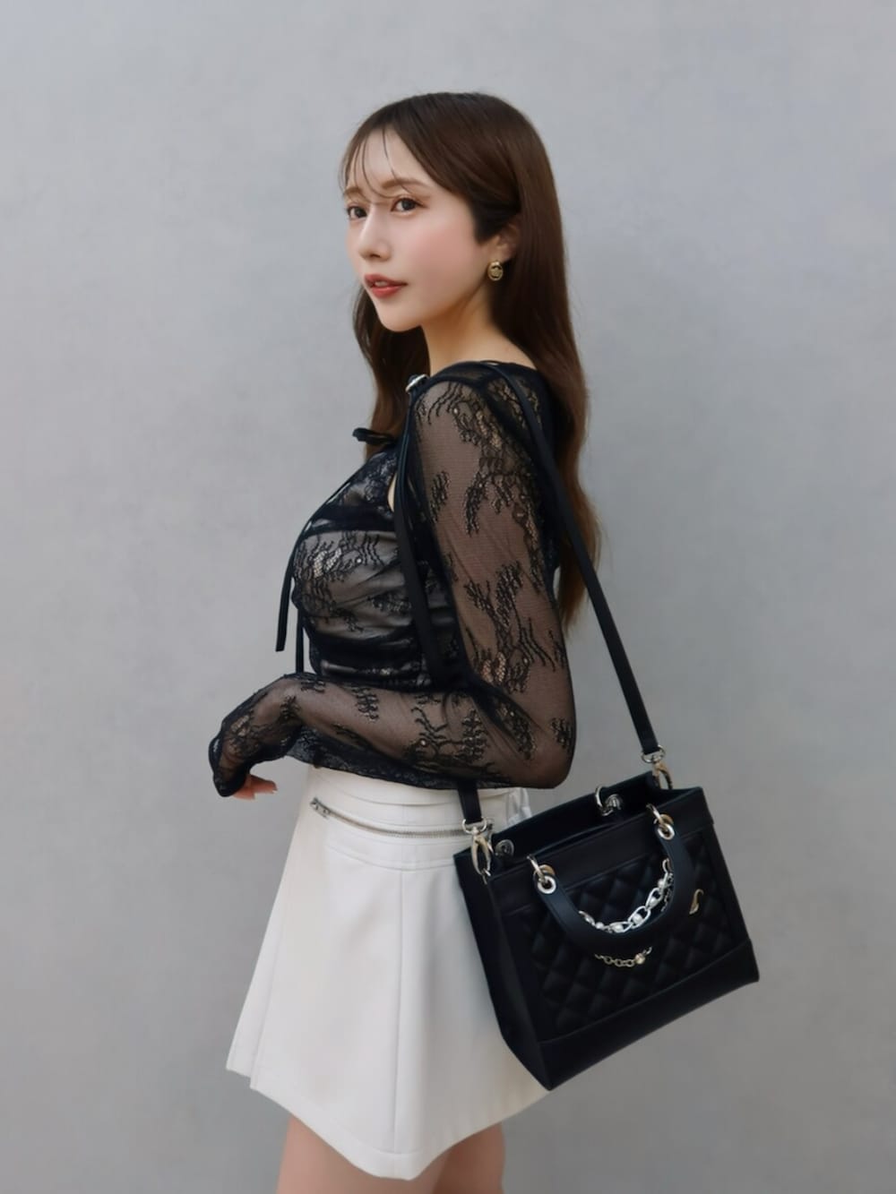 ブラック系のシャツ/ブラウス、ホワイト系のスカート、ブラック系のブーツを着用したレディースの夏コーディネートの3枚目の写真