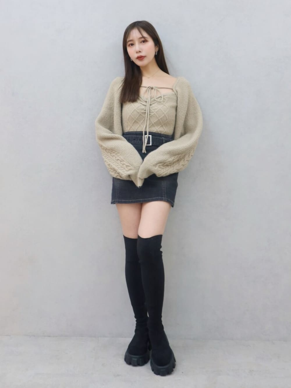 ベージュ系のニット/セーター、ブラック系のデニムスカート、ブラック系のブーツを着用したレディースの冬コーディネートの2枚目の写真