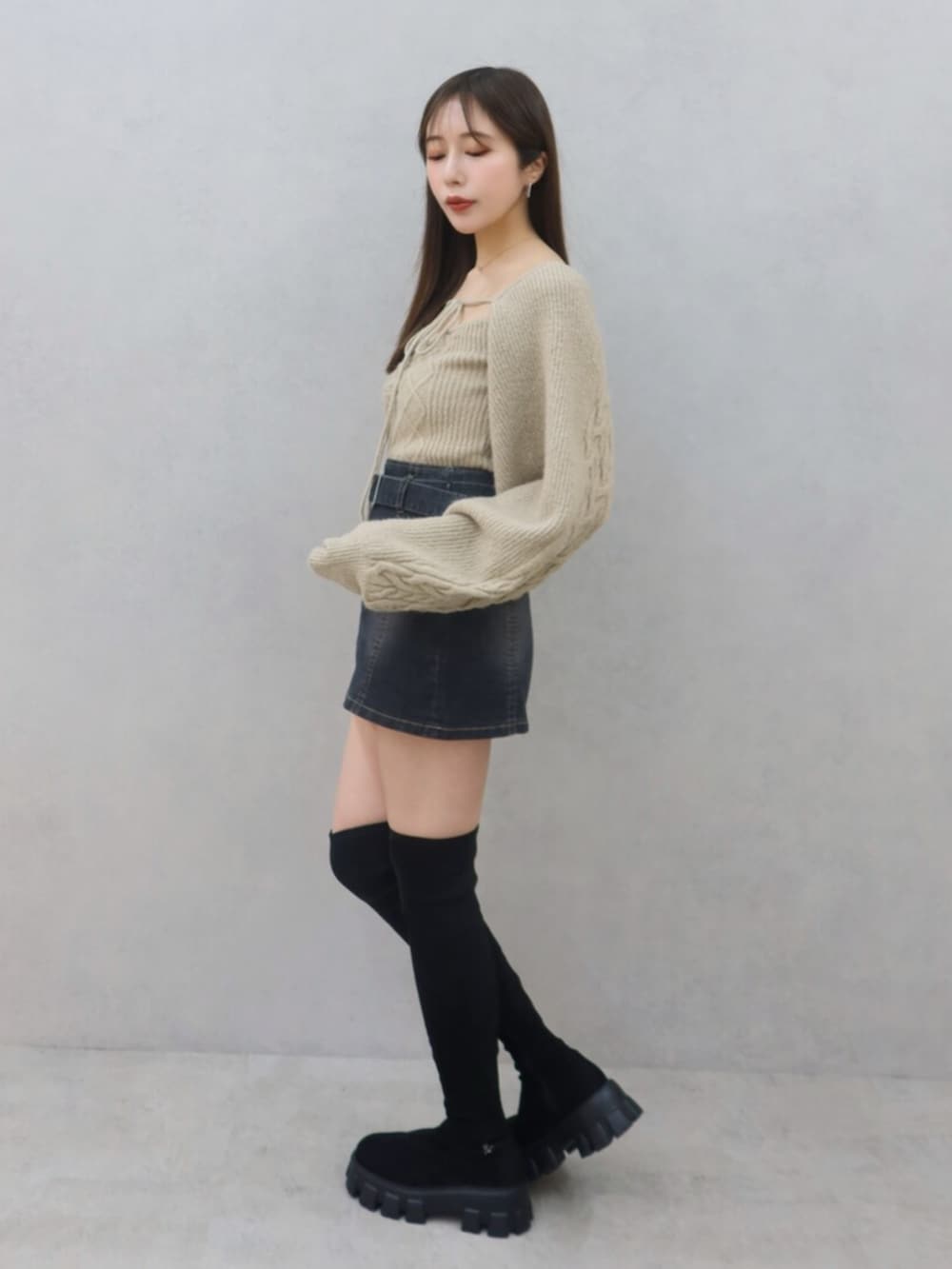 ベージュ系のニット/セーター、ブラック系のデニムスカート、ブラック系のブーツを着用したレディースの冬コーディネートの3枚目の写真