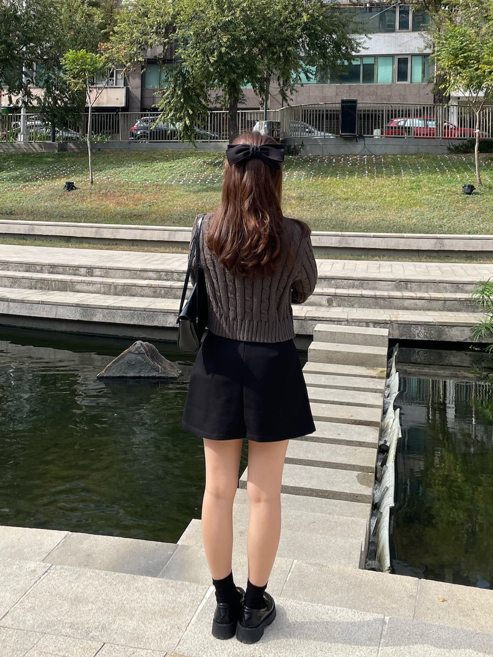 グレー系のニット/セーター、ブラック系のスカート、ブラック系のローファーを着用したレディースの冬コーディネートの3枚目の写真