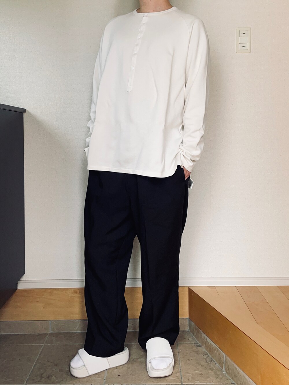 ブラック系のスラックス、ホワイト系のサンダルを着用したメンズの秋コーディネートの2枚目の写真