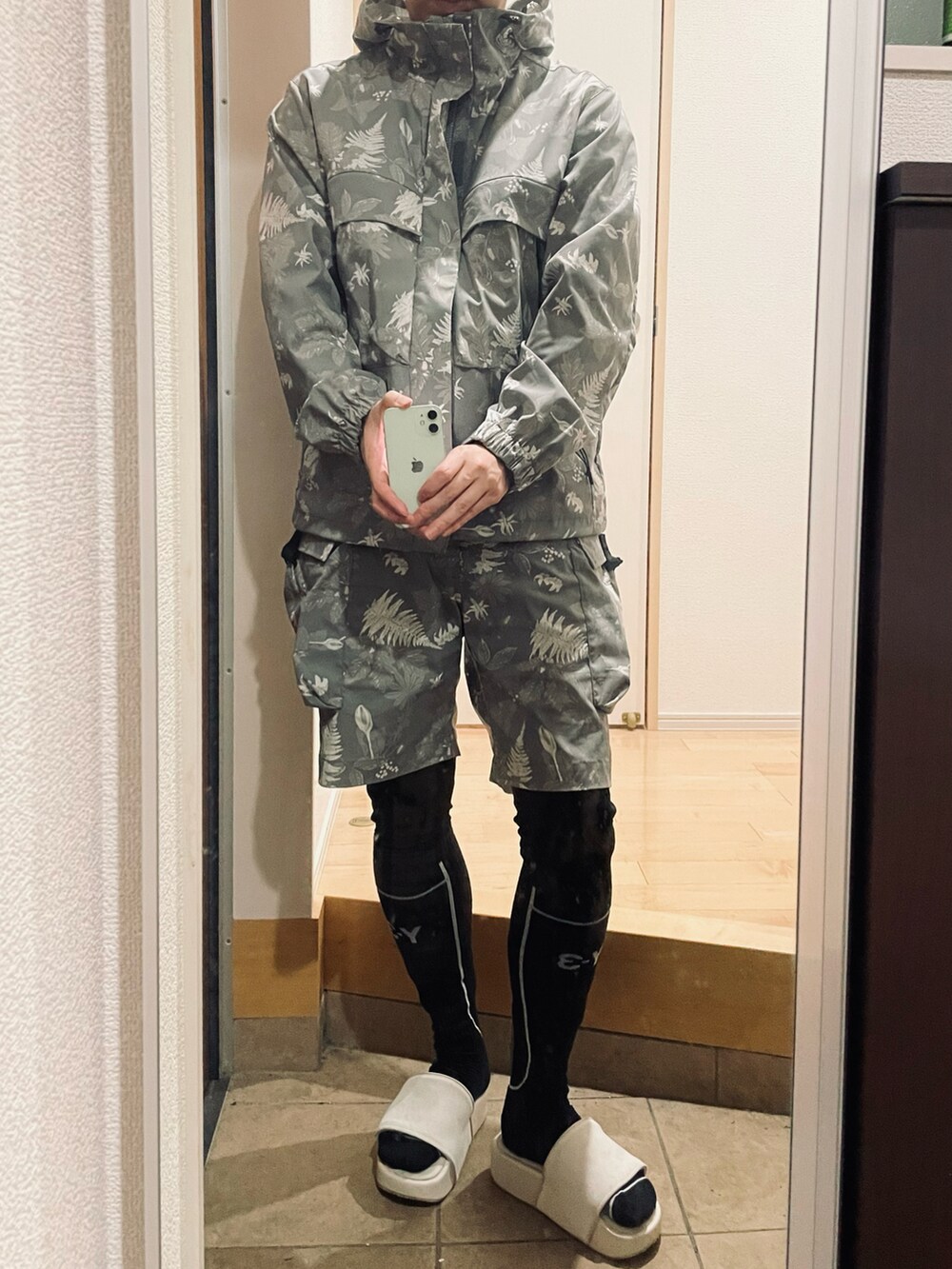 グレー系のその他パンツ、ホワイト系のサンダル、グレー系のマウンテンパーカーを着用したメンズの秋コーディネートの2枚目の写真