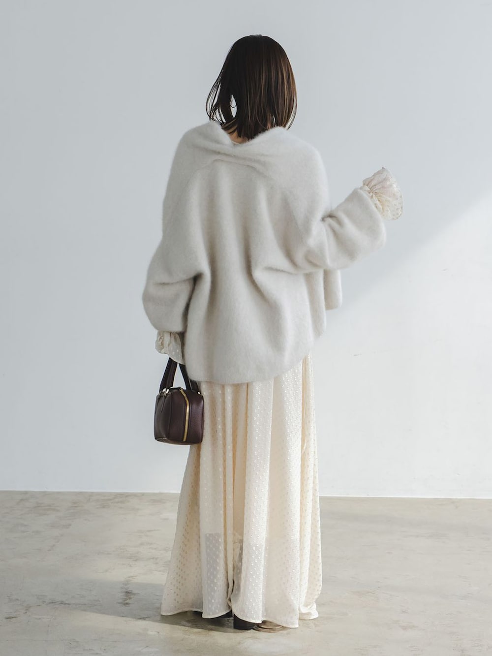 ベージュ系のワンピース、ベージュ系のカーディガン/ボレロ、ブラウン系のボストンバッグを着用したレディースの秋コーディネートの3枚目の写真