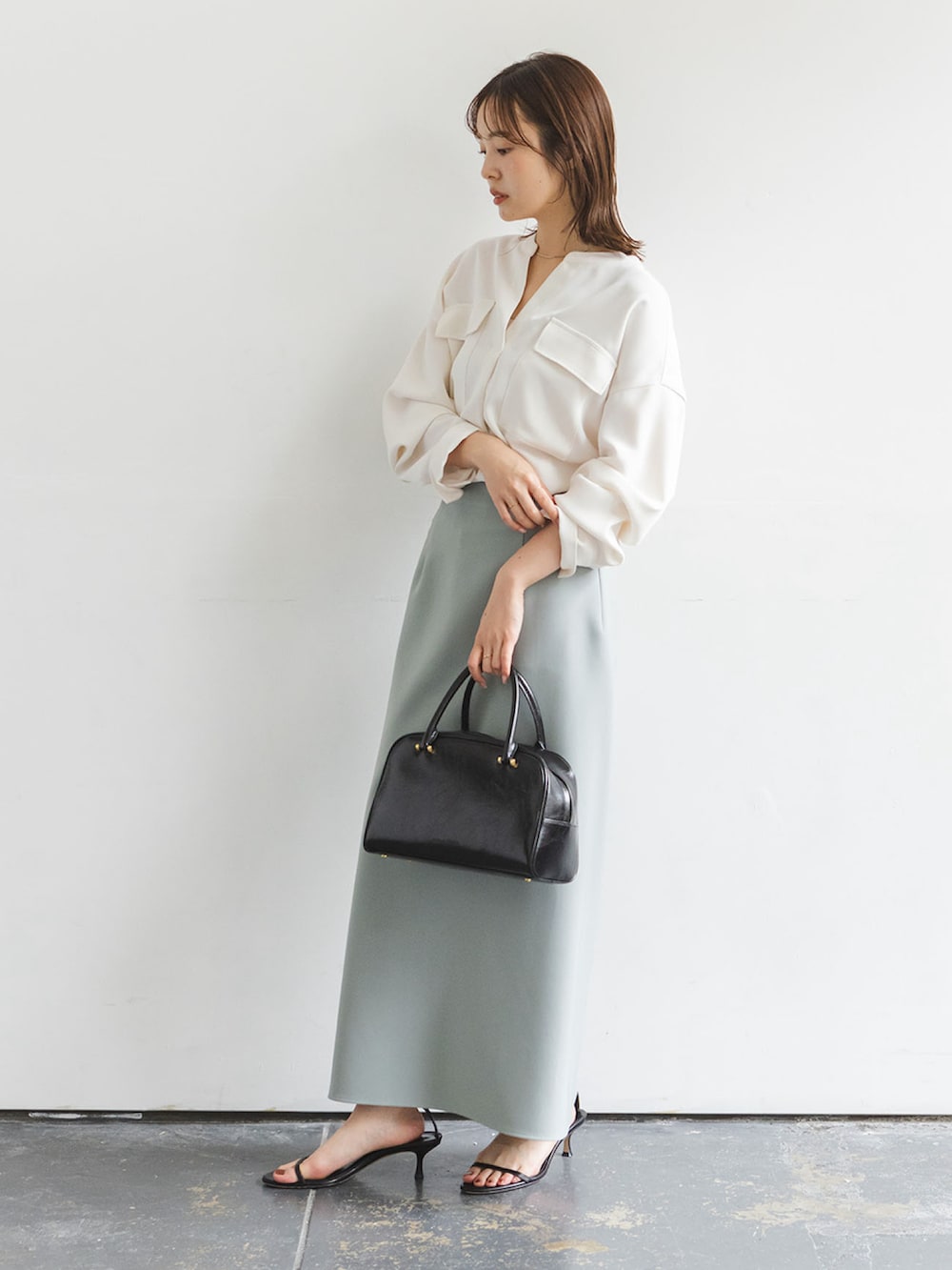 ホワイト系のシャツ/ブラウス、グリーン系のスカート、ブラック系のサンダルを着用したレディースの秋コーディネートの2枚目の写真