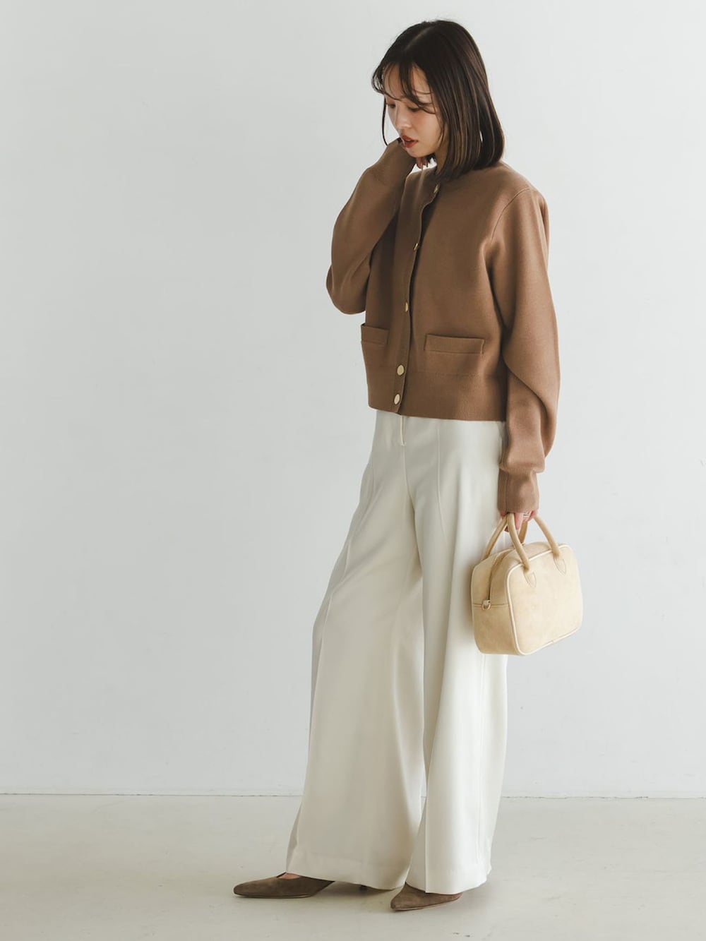 イエロー系のカーディガン/ボレロ、ホワイト系のスラックス、ベージュ系のボストンバッグを着用したレディースの冬コーディネートの2枚目の写真