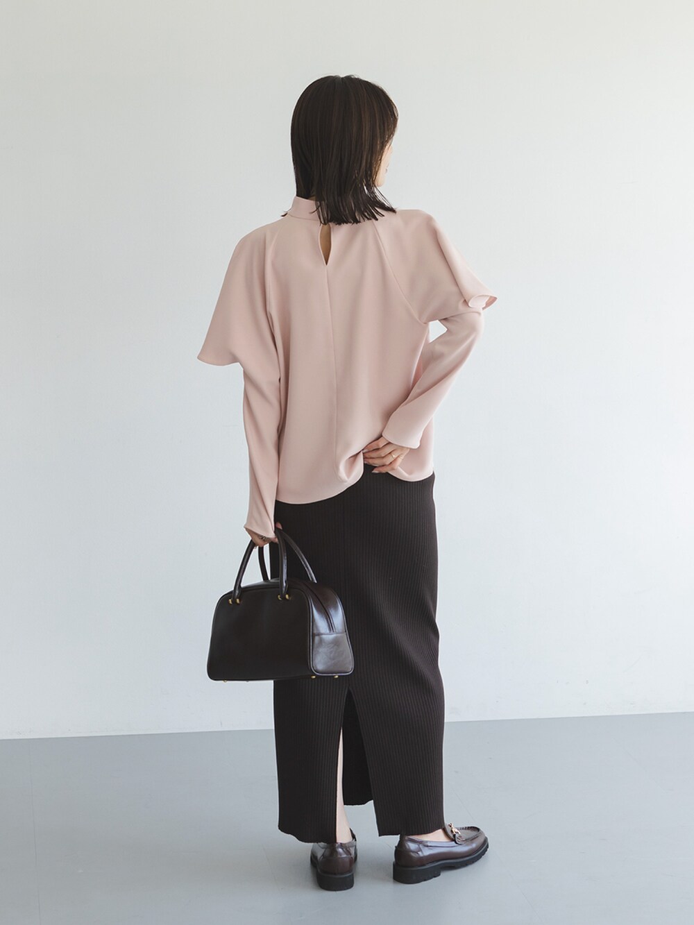 ピンク系のシャツ/ブラウス、ブラウン系のスカート、ブラウン系のハンドバッグを着用したレディースの秋コーディネートの3枚目の写真