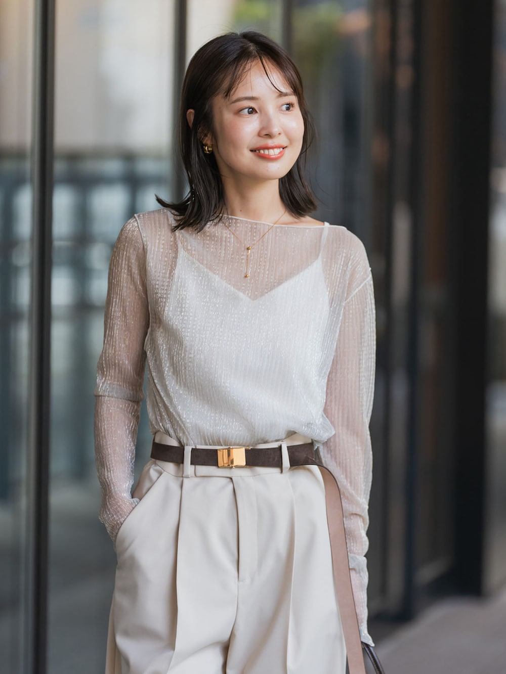 ベージュ系のTシャツ/カットソー、ベージュ系のスラックス、ブラウン系のハンドバッグを着用したレディースの夏コーディネートの3枚目の写真