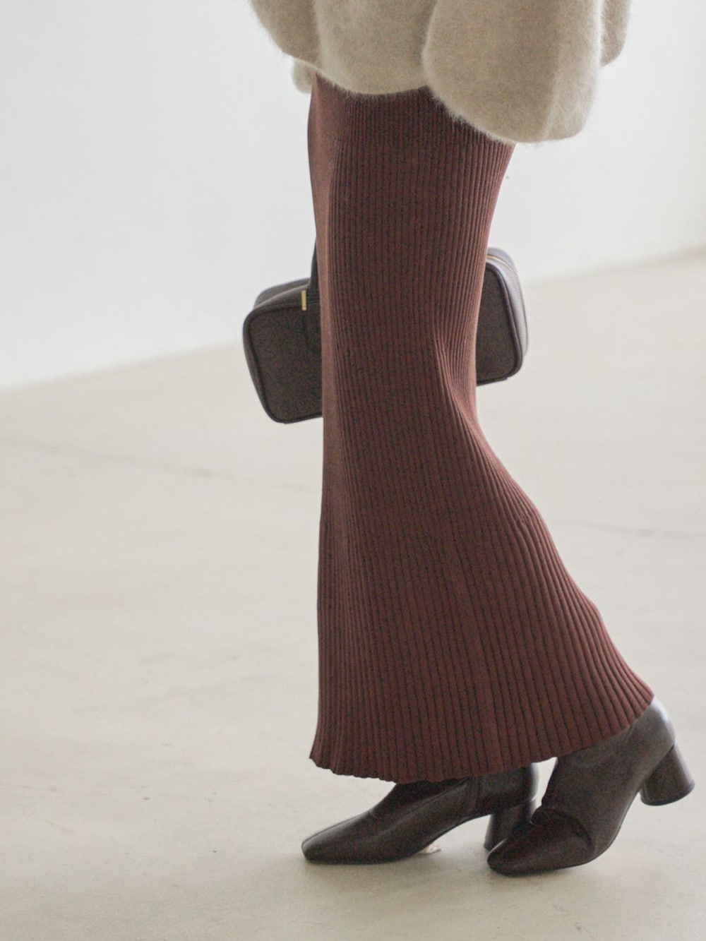 ベージュ系のニット/セーター、ブラウン系のスカート、ブラウン系のブーツを着用したレディースの秋コーディネートの4枚目の写真