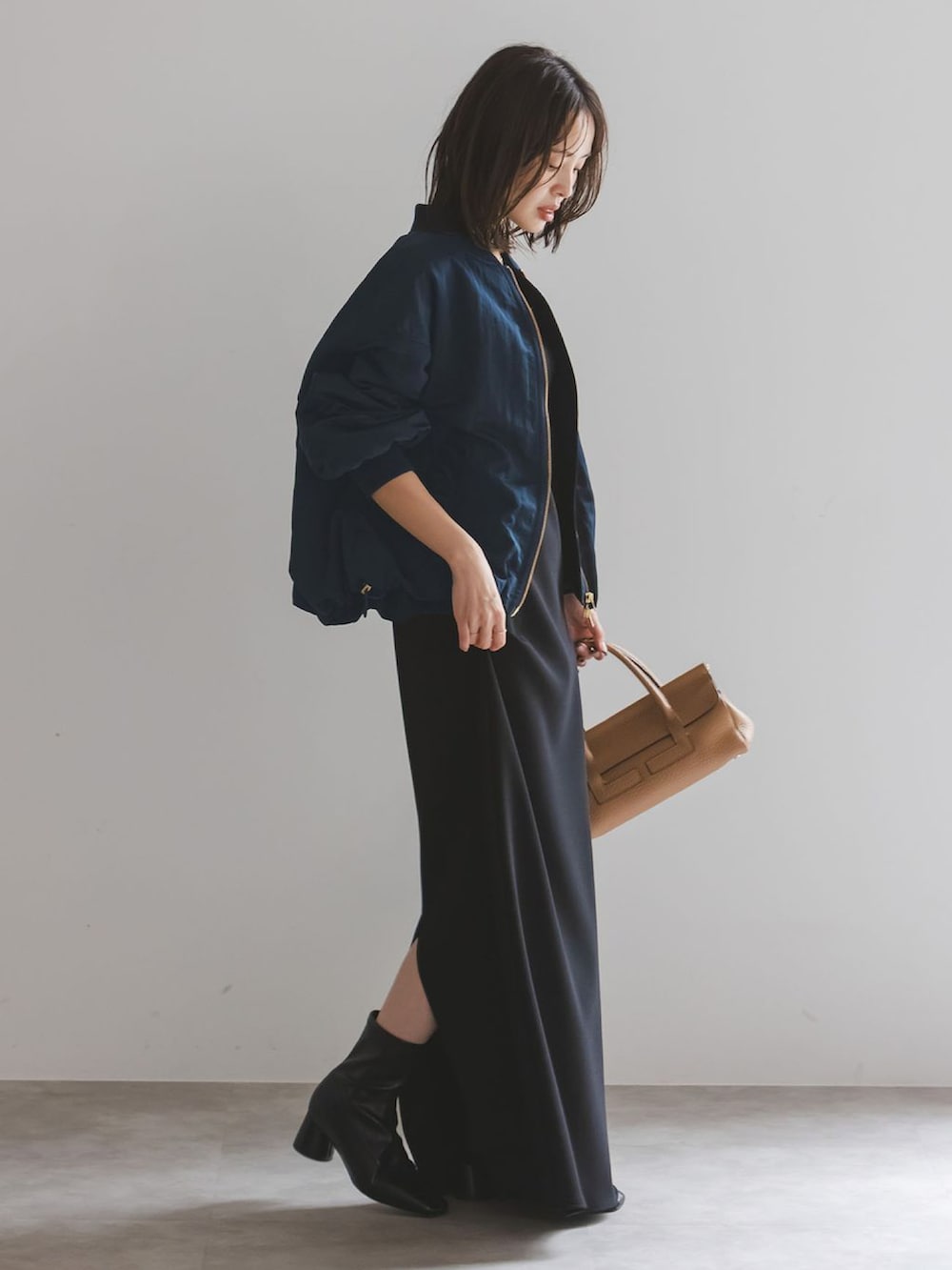 ブルー系のMA-1、グリーン系のワンピース、イエロー系のボストンバッグを着用したレディースの秋コーディネートの2枚目の写真