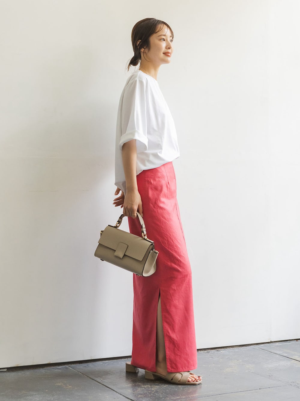レッド系のスカート、ベージュ系のショルダーバッグ、ホワイト系のTシャツ/カットソーを着用したレディースの夏コーディネートの2枚目の写真