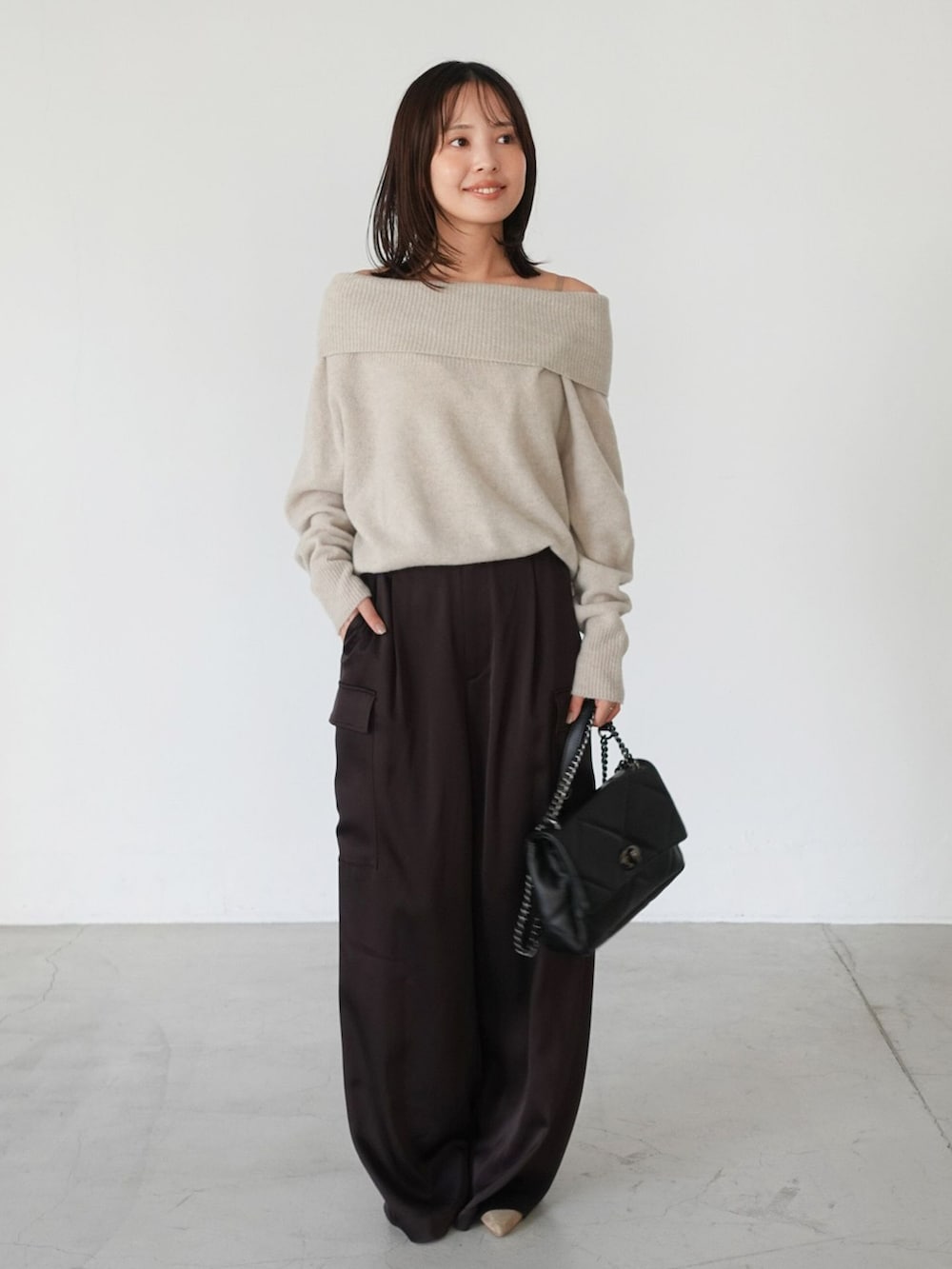 ブラウン系のカーゴパンツ、ベージュ系のニット/セーター、ブラック系のショルダーバッグを着用したレディースの夏コーディネートの5枚目の写真