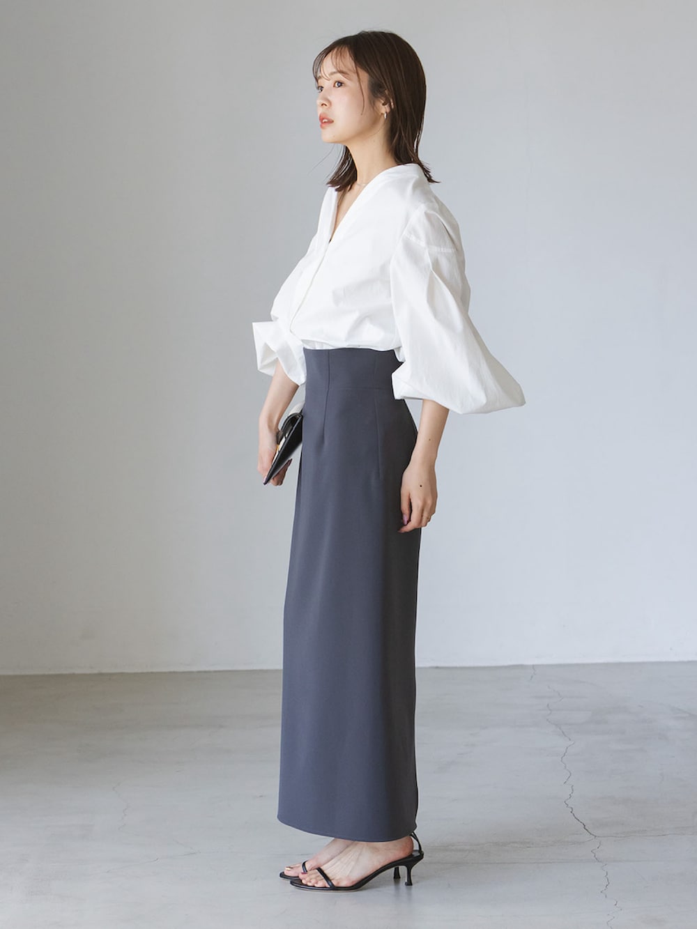 ホワイト系のシャツ/ブラウス、ブラック系のサンダル、ホワイト系のクラッチバッグを着用したレディースの夏コーディネートの2枚目の写真