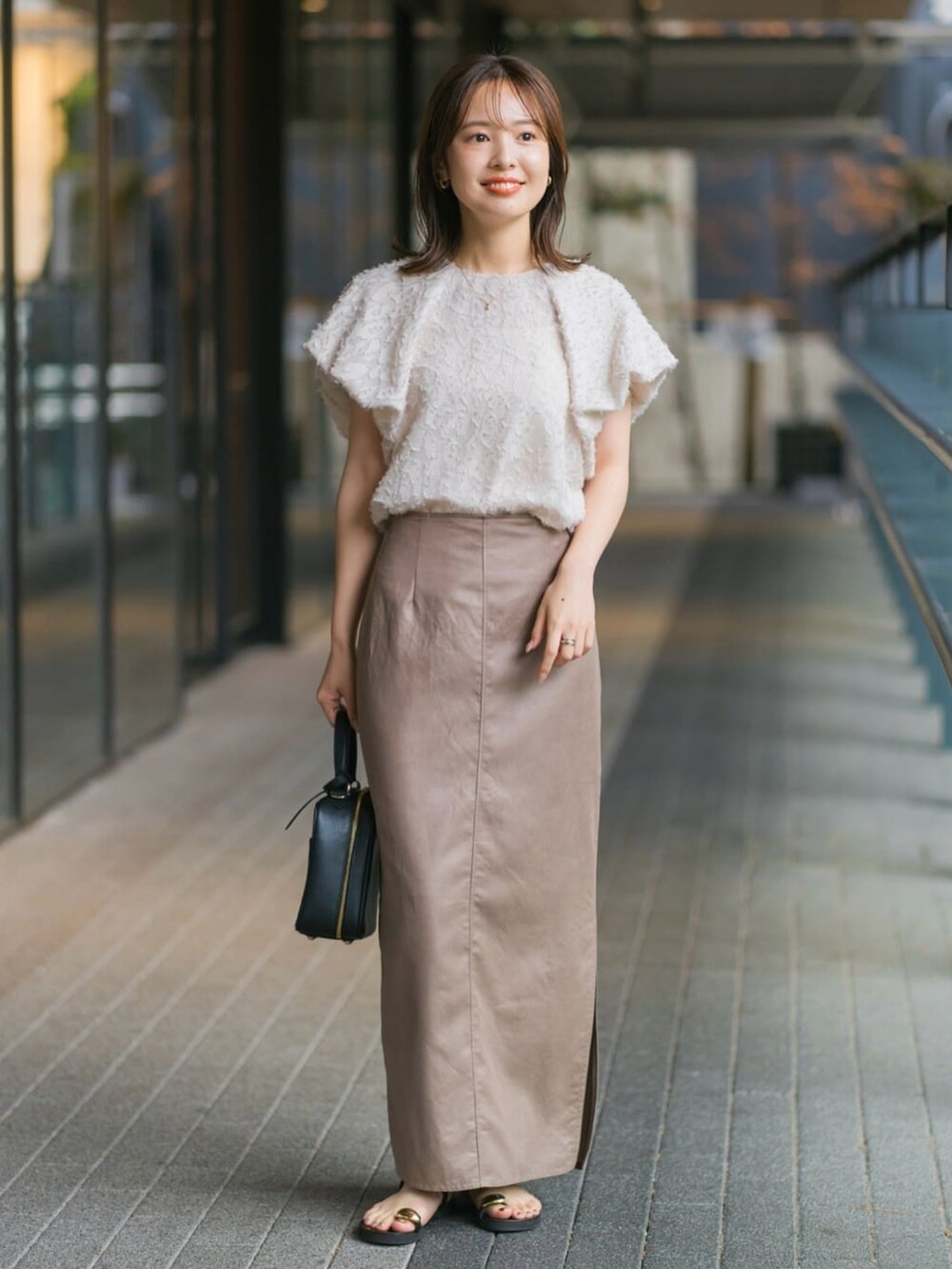 ブラウン系のスカート、ベージュ系のシャツ/ブラウスを着用したレディースの夏コーディネートの2枚目の写真