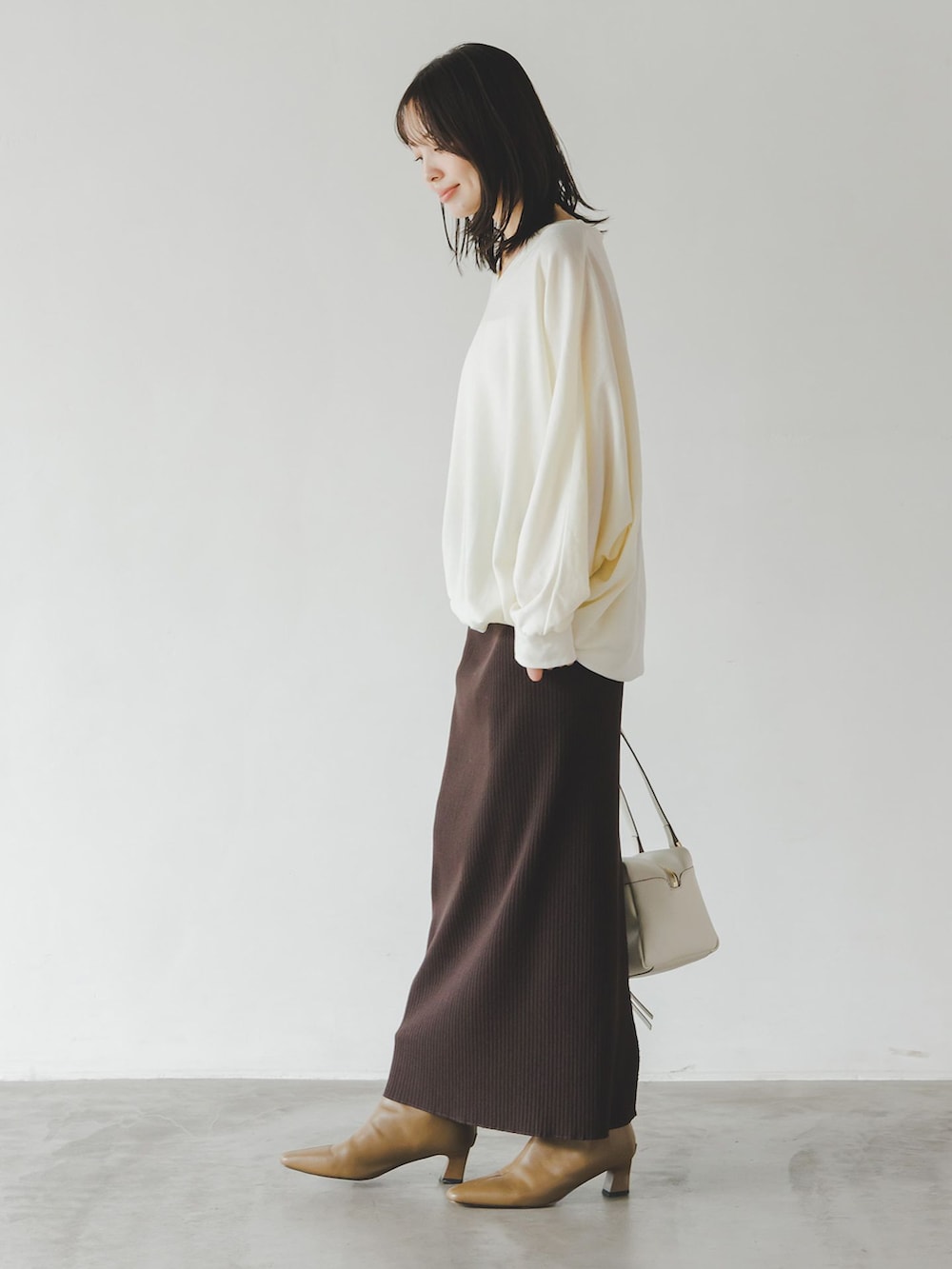 ブラウン系のスカート、ホワイト系のTシャツ/カットソー、ホワイト系のショルダーバッグを着用したレディースの秋コーディネートの2枚目の写真