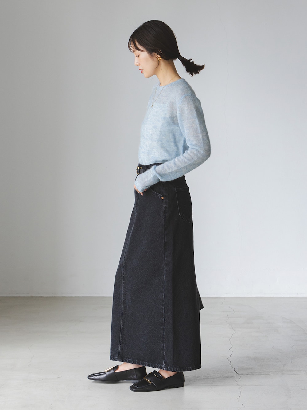 ブルー系のニット/セーター、ブラック系のデニムスカート、ブラック系のショルダーバッグを着用したレディースの秋コーディネートの2枚目の写真