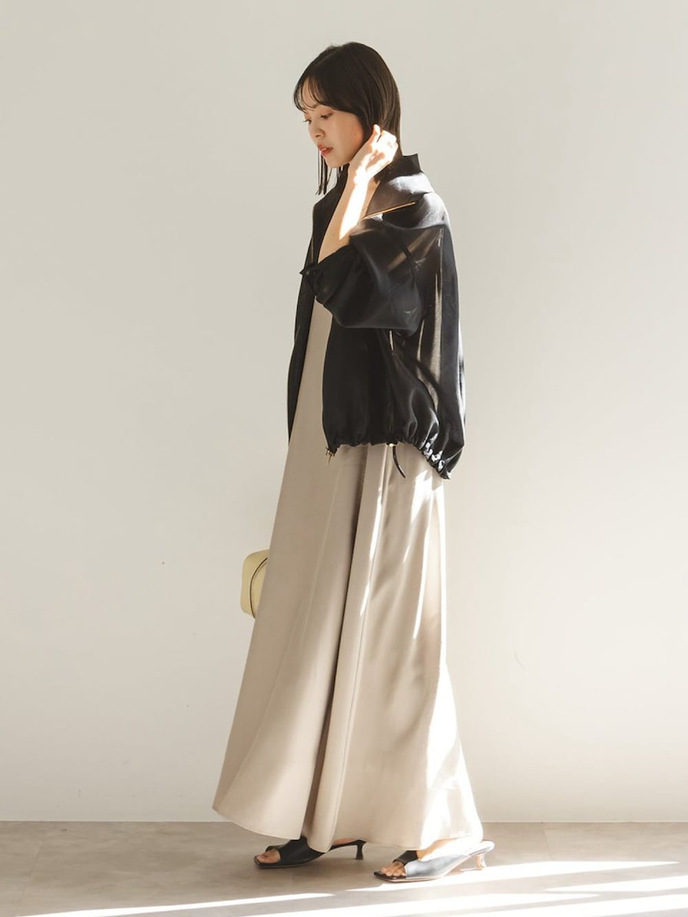 ベージュ系のワンピース、ブラック系のその他アウター、ブラック系のサンダルを着用したレディースの春コーディネートの2枚目の写真