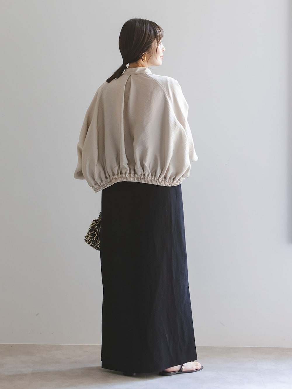 ブラック系のワンピース、ベージュ系のブルゾン、ブラック系のショルダーバッグを着用したレディースの春コーディネートの3枚目の写真