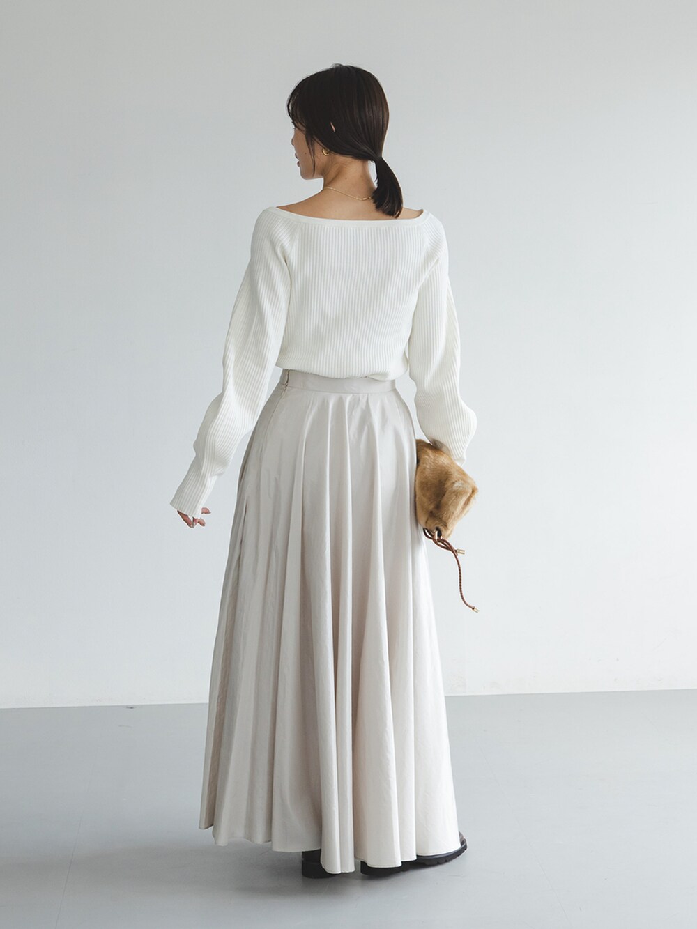 ホワイト系のニット/セーター、ベージュ系のスカート、ブラウン系のローファーを着用したレディースの秋コーディネートの3枚目の写真