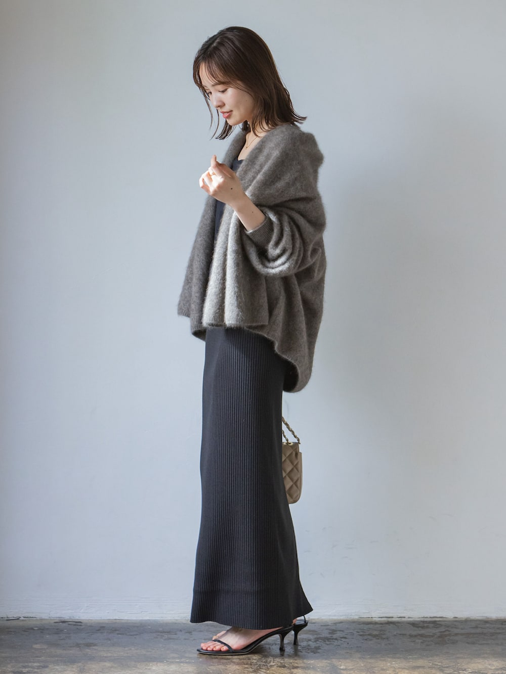 グレー系のカーディガン/ボレロ、ブラック系のスカート、ベージュ系のショルダーバッグを着用したレディースの秋コーディネートの2枚目の写真
