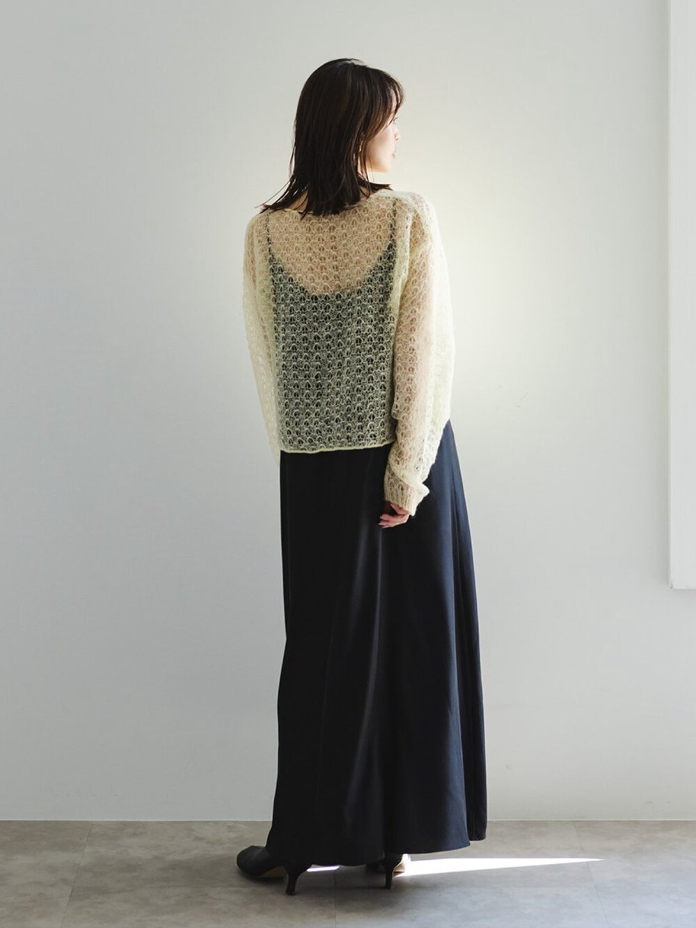 イエロー系のニット/セーター、ブラック系のショルダーバッグ、ブラック系のワンピースを着用したレディースの冬コーディネートの3枚目の写真