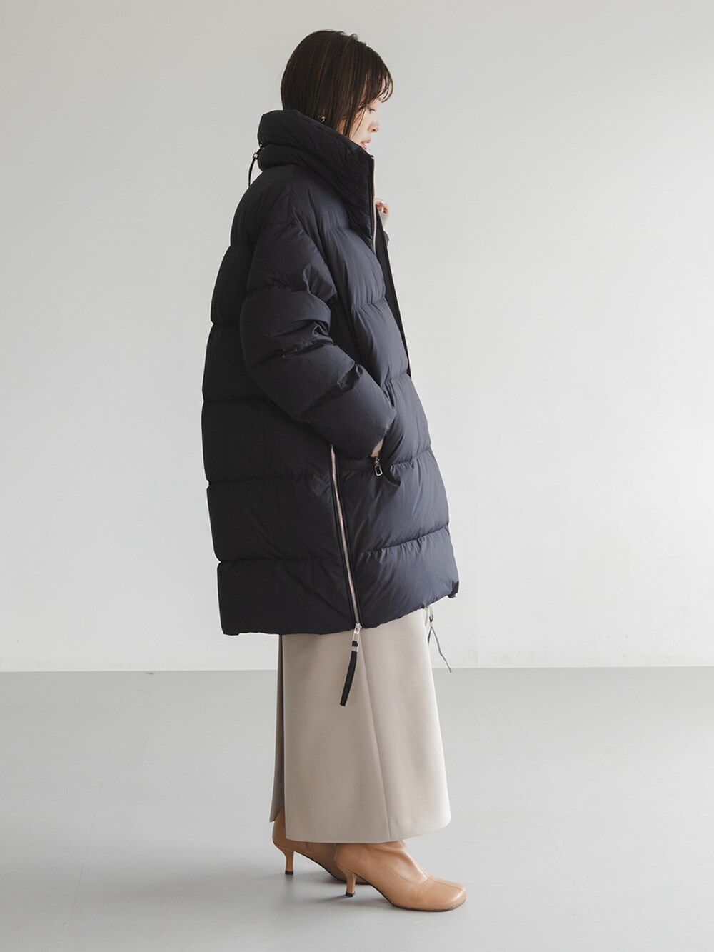 ブラック系のダウンジャケット/コート、ベージュ系のワンピース、イエロー系のブーツを着用したレディースの秋コーディネートの2枚目の写真