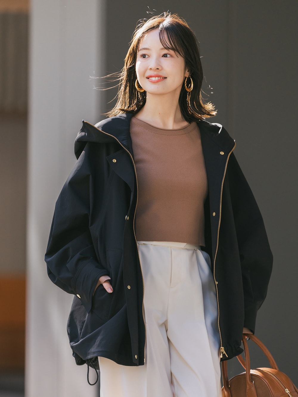 ブラック系のその他アウター、イエロー系のニット/セーター、ベージュ系のスラックスを着用したレディースの冬コーディネートの4枚目の写真