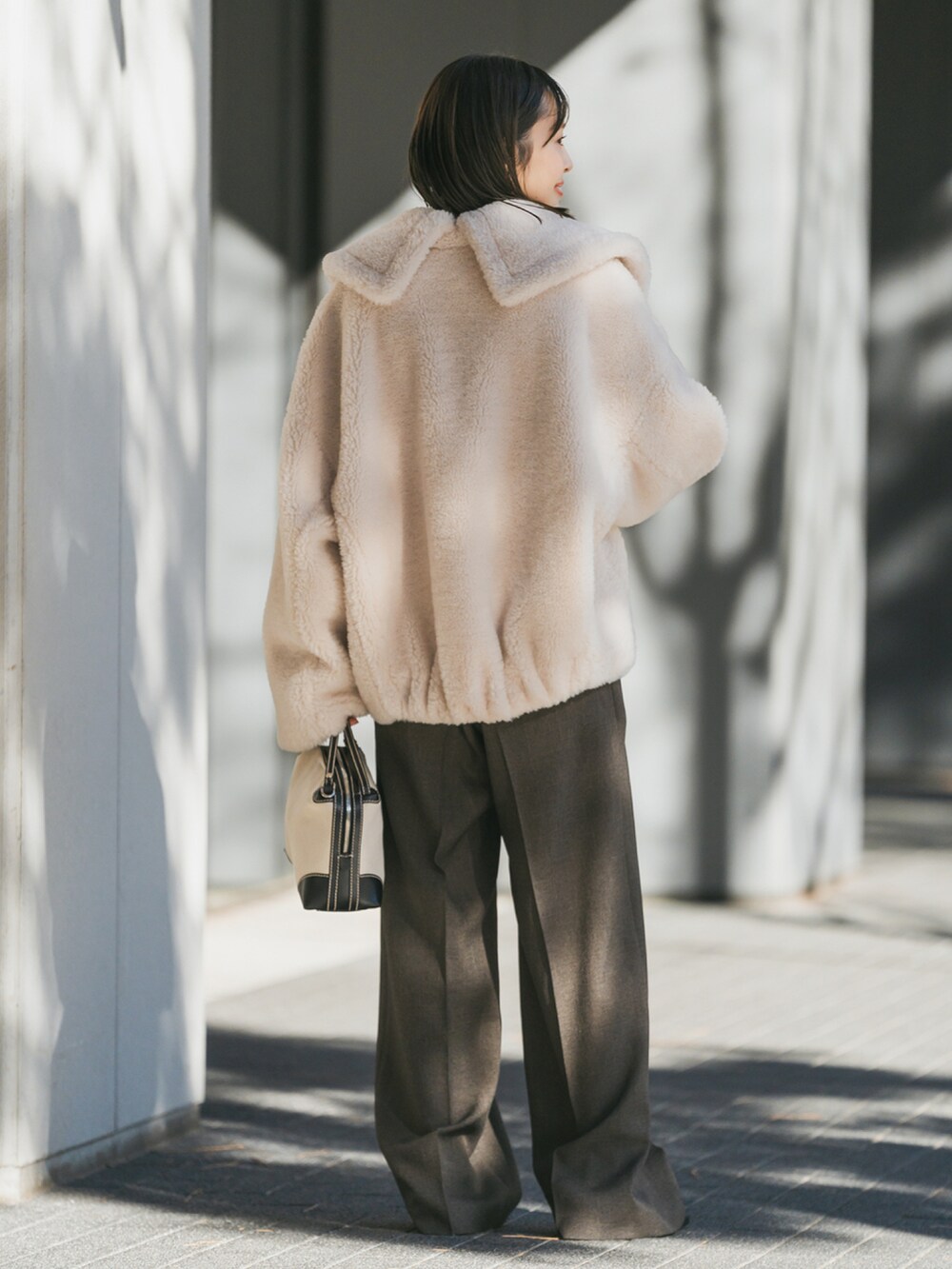 ホワイト系のブルゾン、ホワイト系のTシャツ/カットソー、ブラウン系のスラックスを着用したレディースの冬コーディネートの2枚目の写真