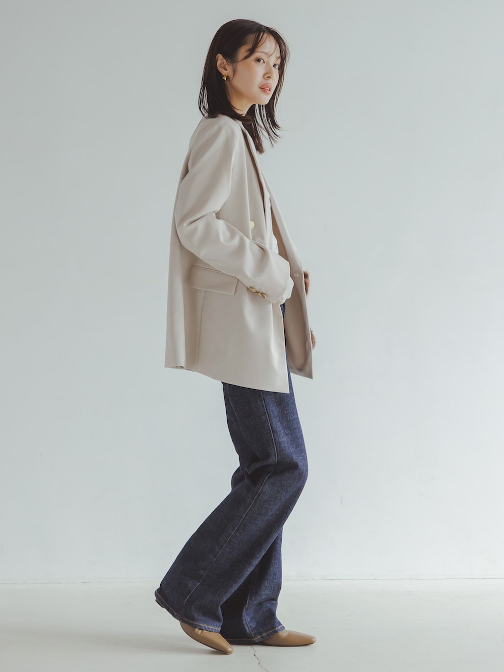 ホワイト系のテーラードジャケット、ブルー系のデニムパンツ、ホワイト系のTシャツ/カットソーを着用したレディースの秋コーディネートの2枚目の写真