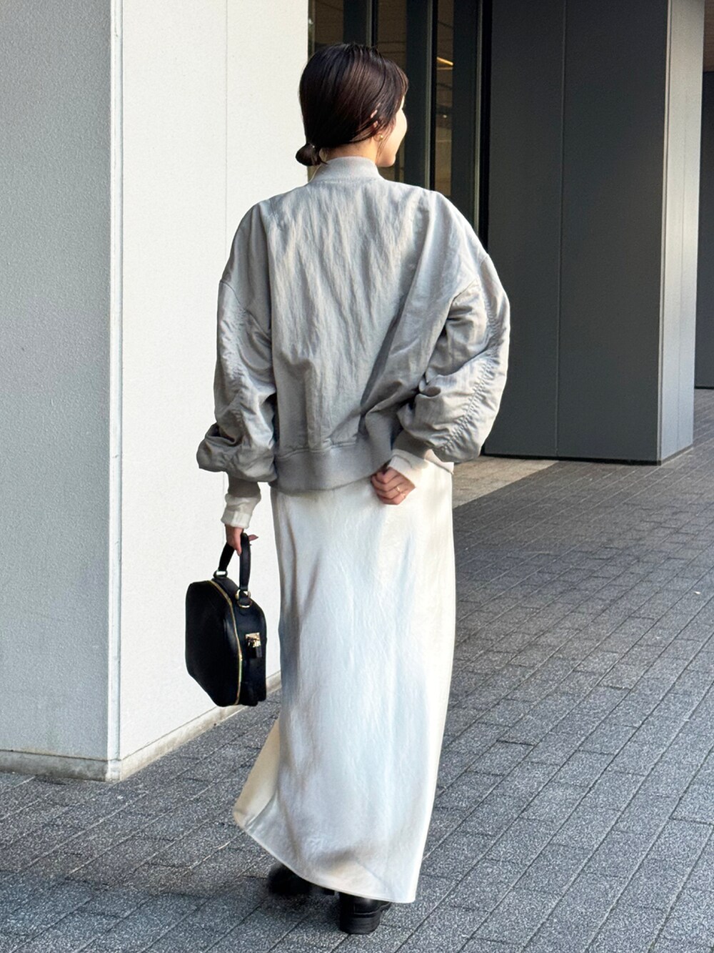 グレー系のMA-1、ホワイト系のニット/セーター、ホワイト系のスカートを着用したレディースの秋コーディネートの2枚目の写真