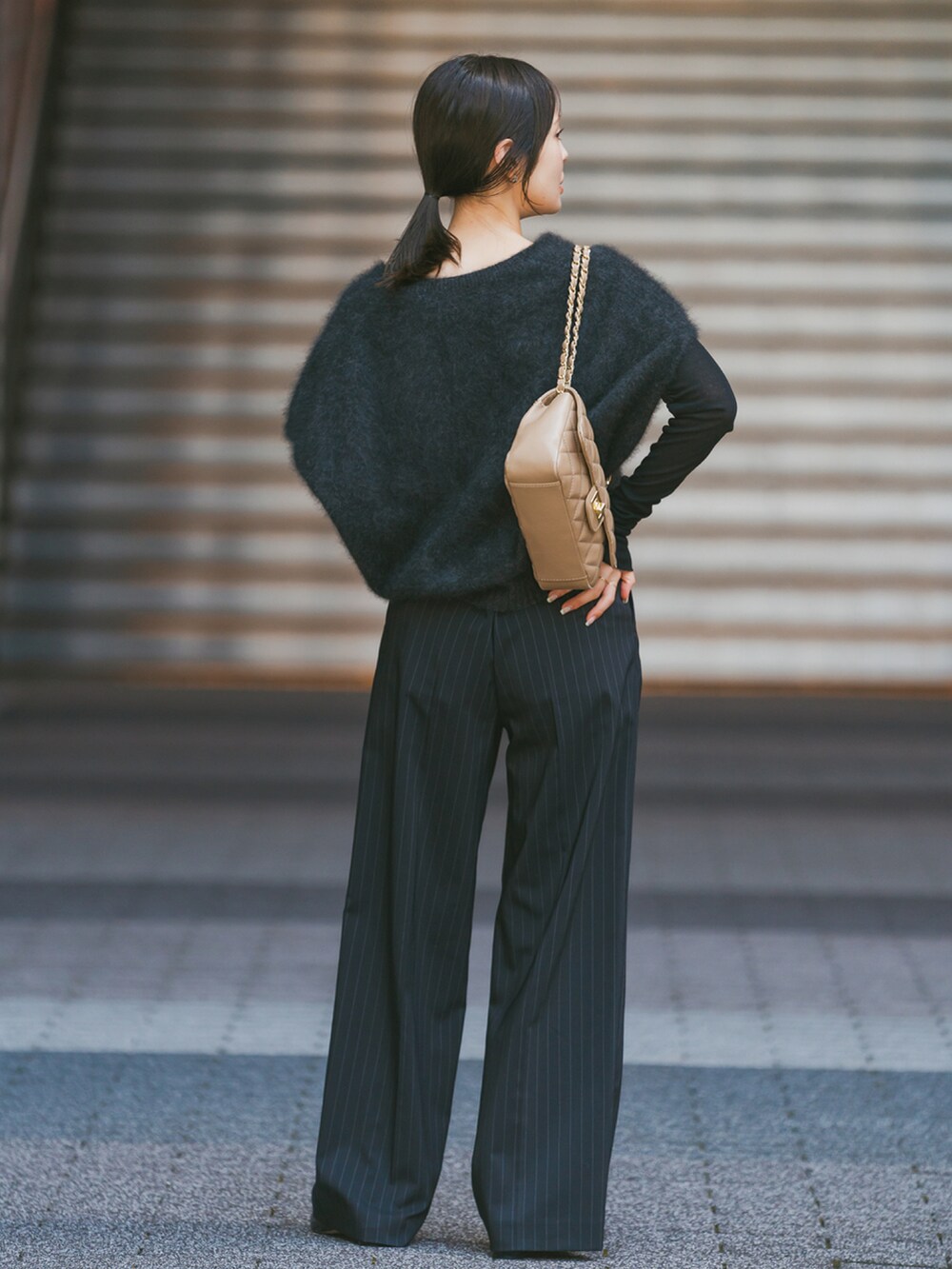 グレー系のベスト、ブラック系のTシャツ/カットソー、ベージュ系のショルダーバッグを着用したレディースの秋コーディネートの2枚目の写真