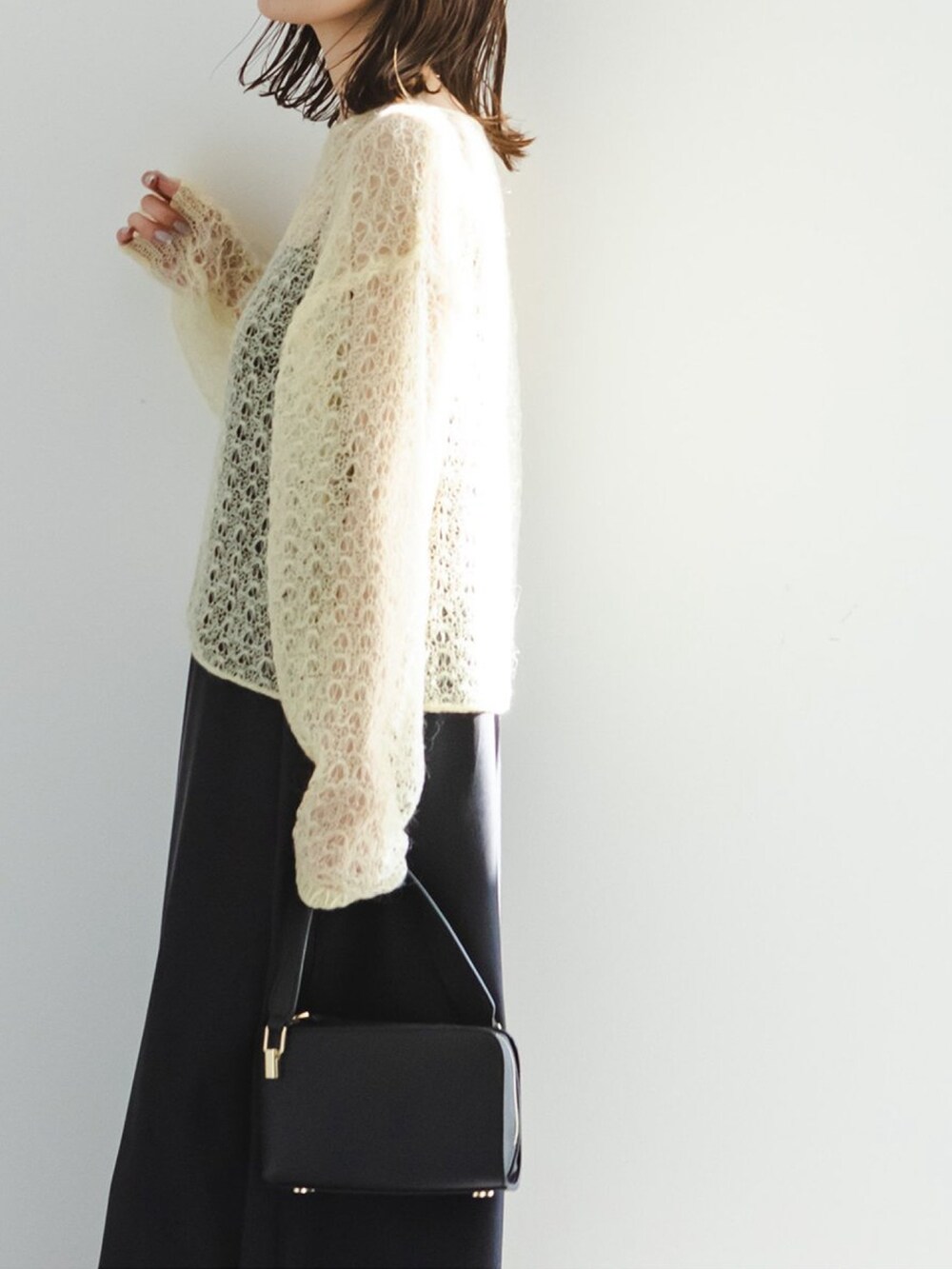 イエロー系のニット/セーター、ブラック系のショルダーバッグ、ブラック系のワンピースを着用したレディースの冬コーディネートの4枚目の写真