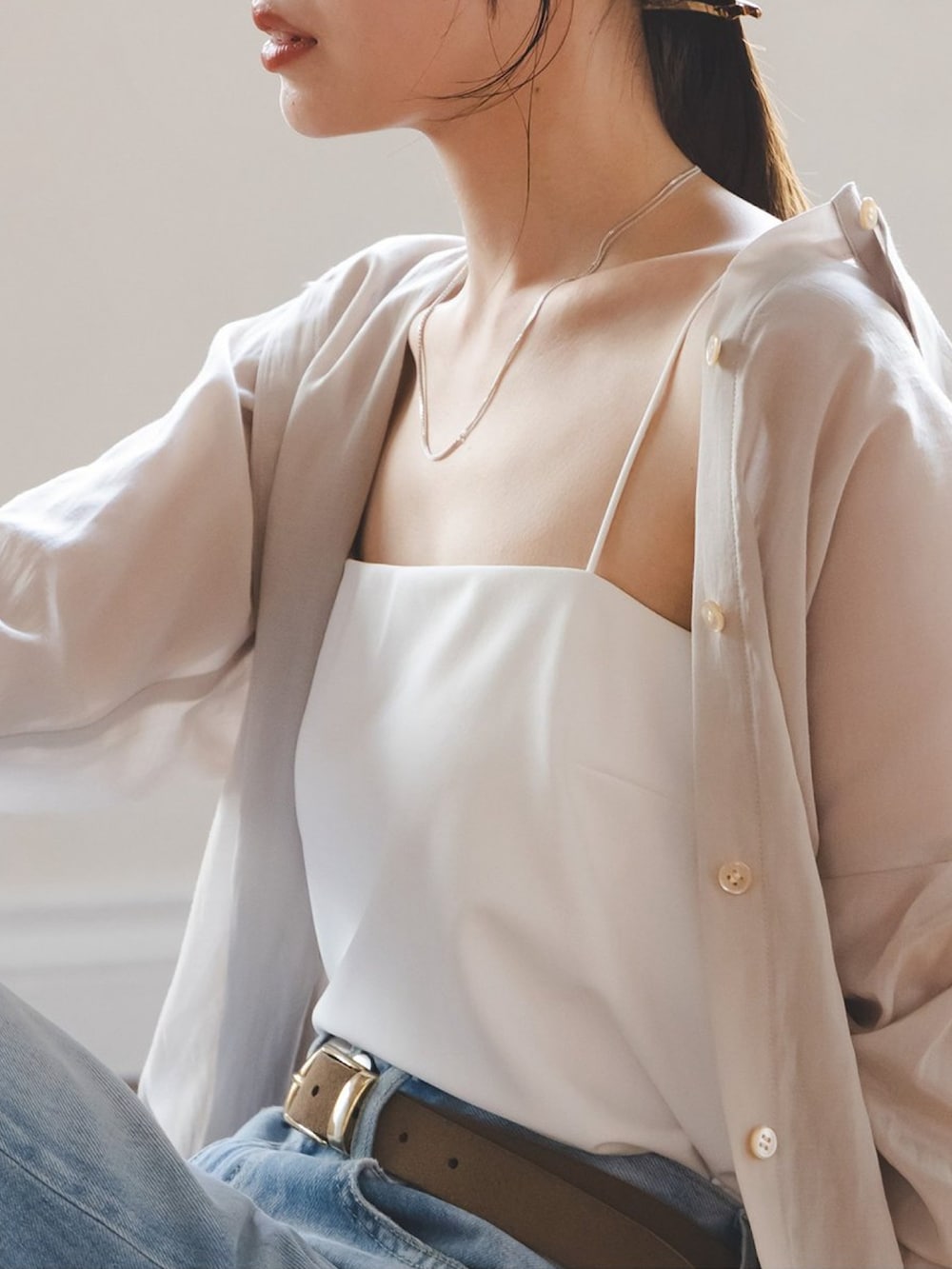 ベージュ系のシャツ/ブラウス、ホワイト系のキャミソール、ブルー系のデニムパンツを着用したレディースの春コーディネートの2枚目の写真