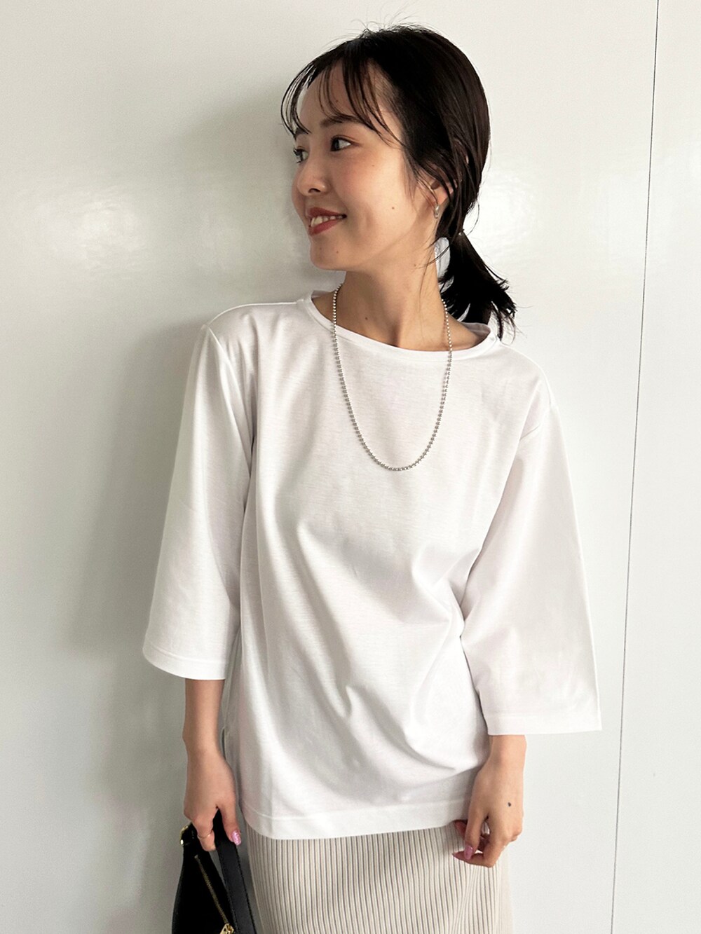 ホワイト系のTシャツ/カットソー、グレー系のスカート、ブラック系のハンドバッグを着用したレディースの春コーディネートの3枚目の写真