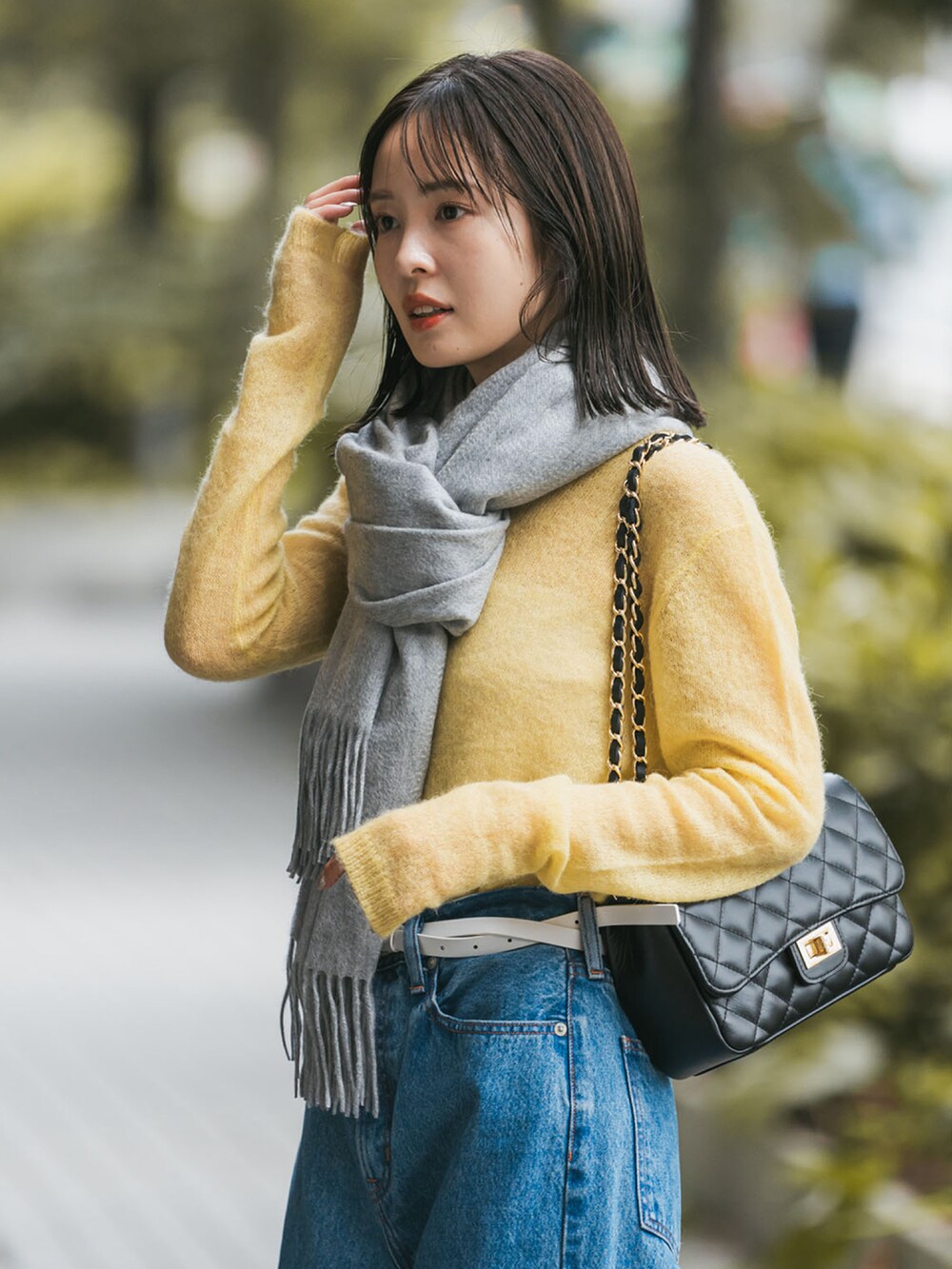 イエロー系のニット/セーター、ブラック系のショルダーバッグ、ブルー系のデニムパンツを着用したレディースの秋コーディネートの3枚目の写真