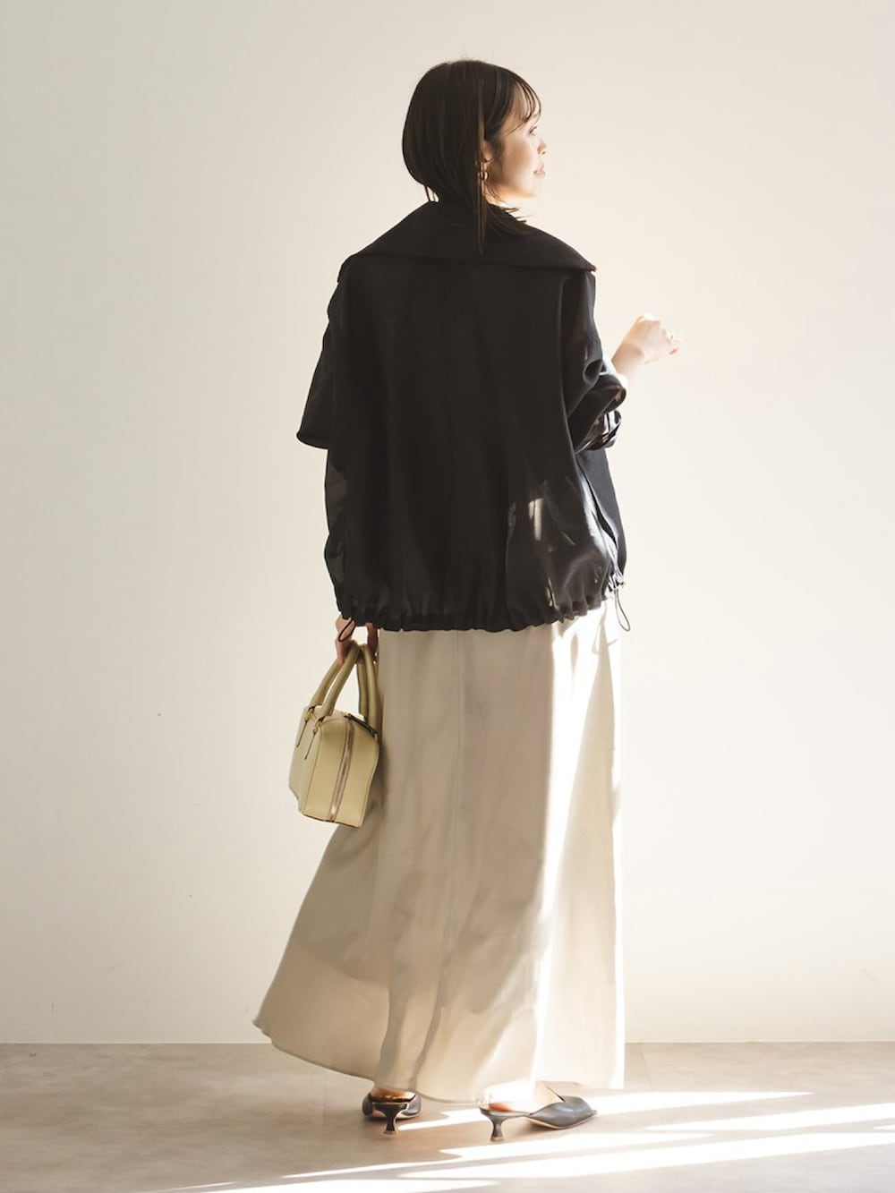 ベージュ系のワンピース、ブラック系のその他アウター、ブラック系のサンダルを着用したレディースの春コーディネートの3枚目の写真