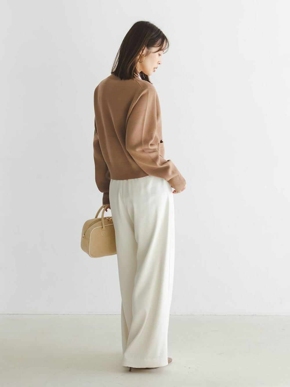 イエロー系のカーディガン/ボレロ、ホワイト系のスラックス、ベージュ系のボストンバッグを着用したレディースの冬コーディネートの3枚目の写真