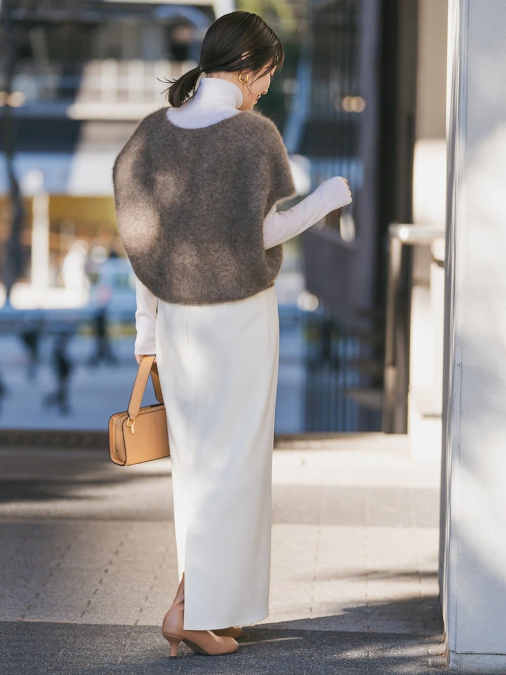 ブラウン系のベスト、ホワイト系のニット/セーター、ホワイト系のスカートを着用したレディースの冬コーディネートの2枚目の写真