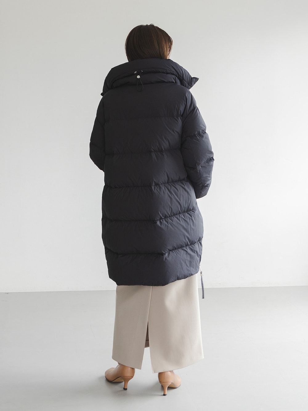 ブラック系のダウンジャケット/コート、ベージュ系のワンピース、イエロー系のブーツを着用したレディースの秋コーディネートの3枚目の写真