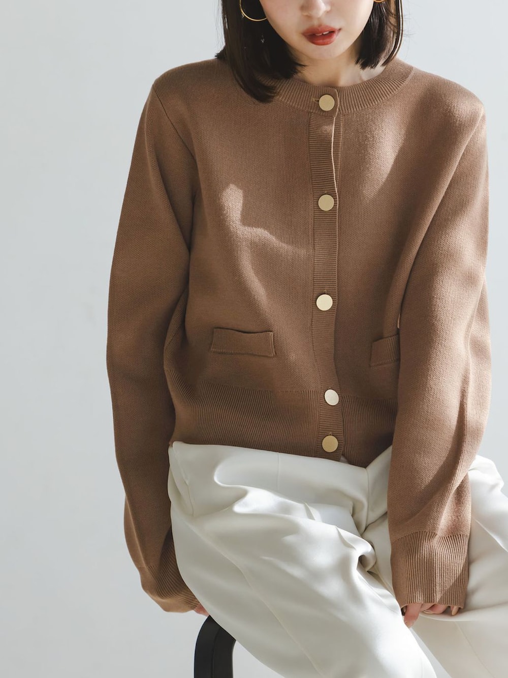 イエロー系のカーディガン/ボレロ、ホワイト系のスラックス、ベージュ系のボストンバッグを着用したレディースの冬コーディネートの4枚目の写真