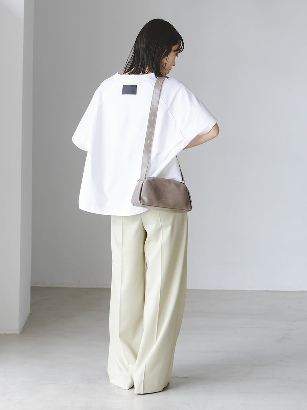 ホワイト系のTシャツ/カットソー、グリーン系のスラックス、グレー系のショルダーバッグを着用したレディースの春コーディネートの2枚目の写真