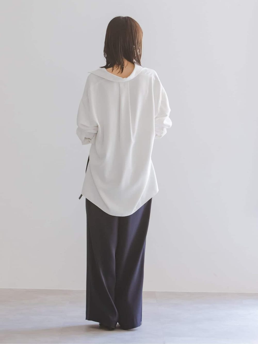 ブルー系のスラックス、ホワイト系のシャツ/ブラウス、ブラック系のショルダーバッグを着用したレディースの夏コーディネートの3枚目の写真