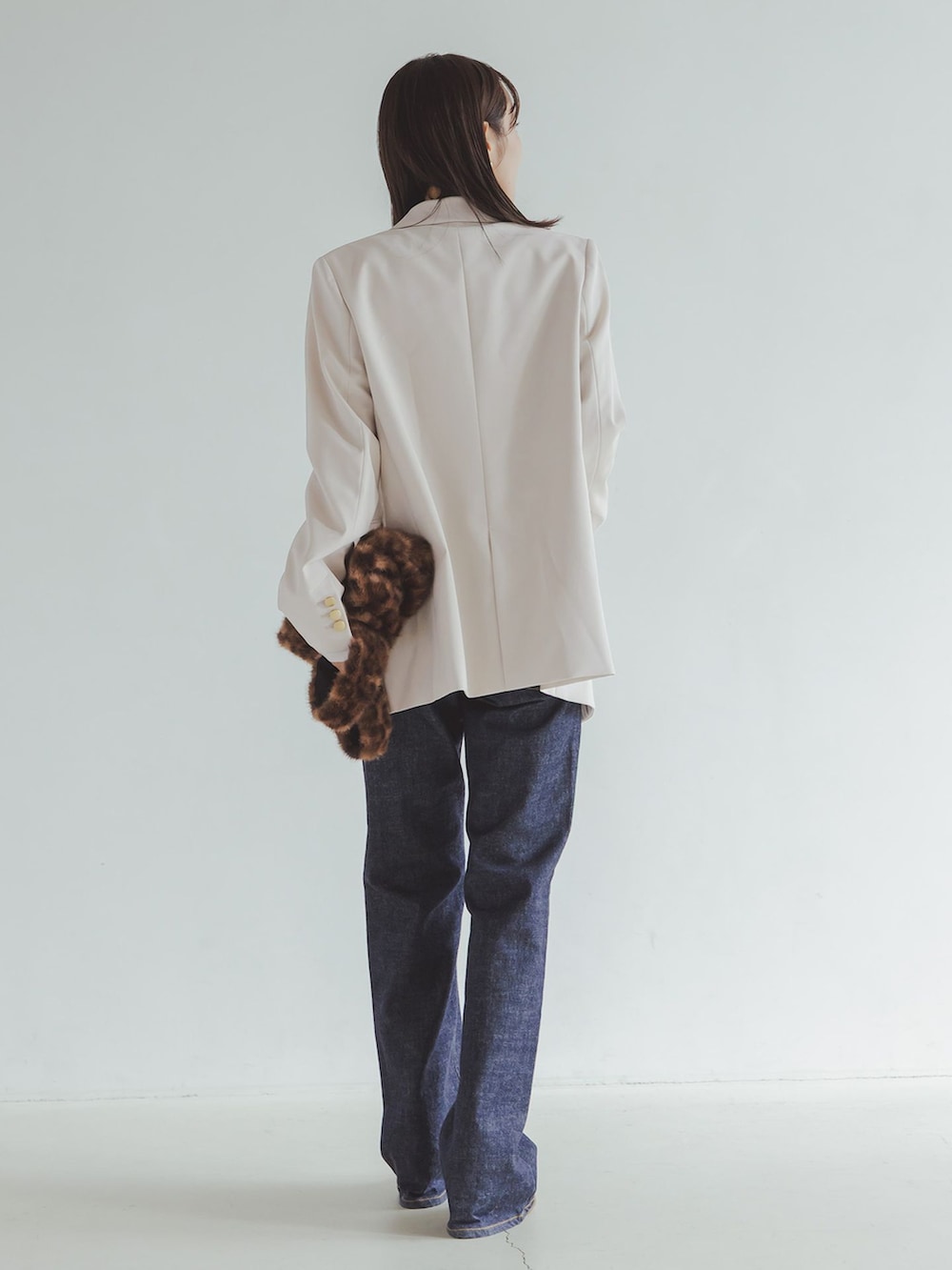 ホワイト系のテーラードジャケット、ブルー系のデニムパンツ、ホワイト系のTシャツ/カットソーを着用したレディースの秋コーディネートの3枚目の写真