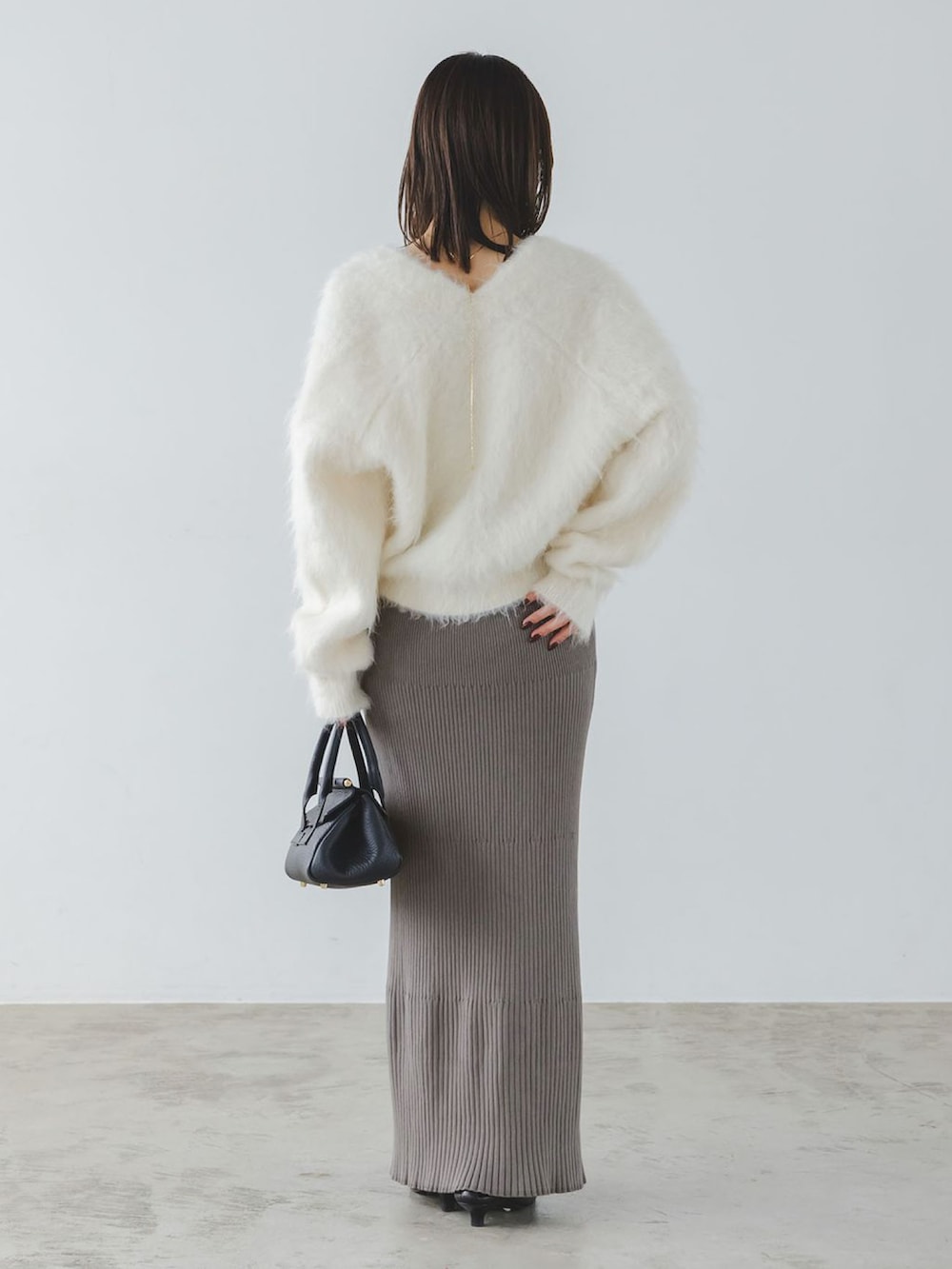 ホワイト系のカーディガン/ボレロ、グレー系のスカート、イエロー系のボストンバッグを着用したレディースの秋コーディネートの3枚目の写真