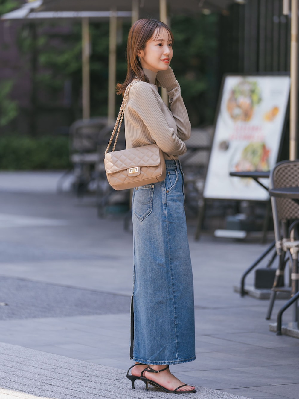 グリーン系のニット/セーター、ブルー系のデニムスカート、ブラック系のサンダルを着用したレディースの夏コーディネートの2枚目の写真