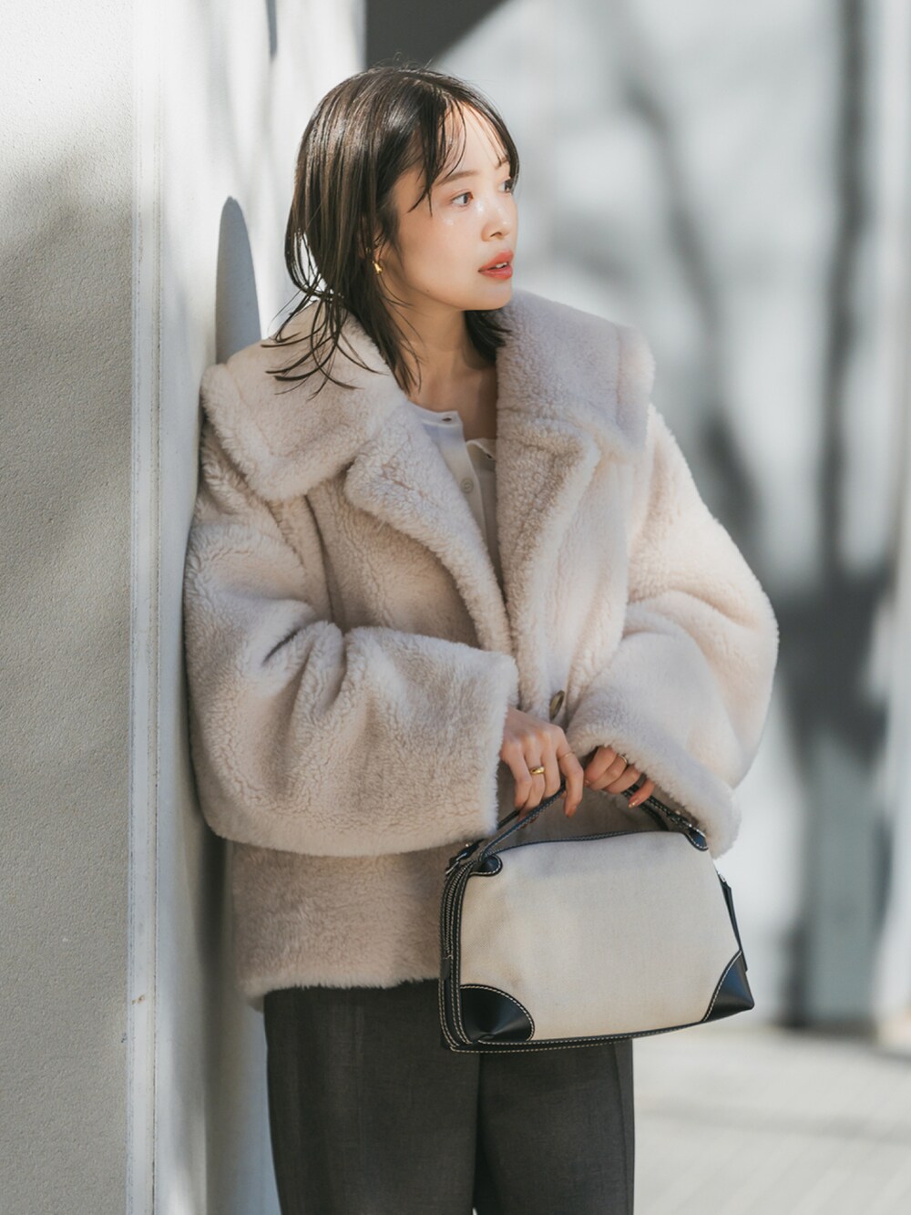 ホワイト系のブルゾン、ホワイト系のTシャツ/カットソー、ブラウン系のスラックスを着用したレディースの冬コーディネートの3枚目の写真