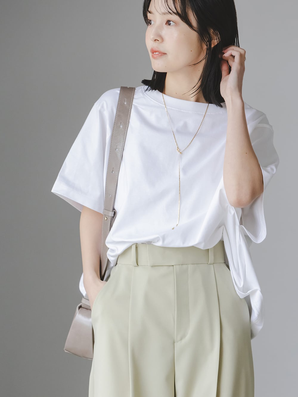 ホワイト系のTシャツ/カットソー、グリーン系のスラックス、グレー系のショルダーバッグを着用したレディースの春コーディネートの3枚目の写真