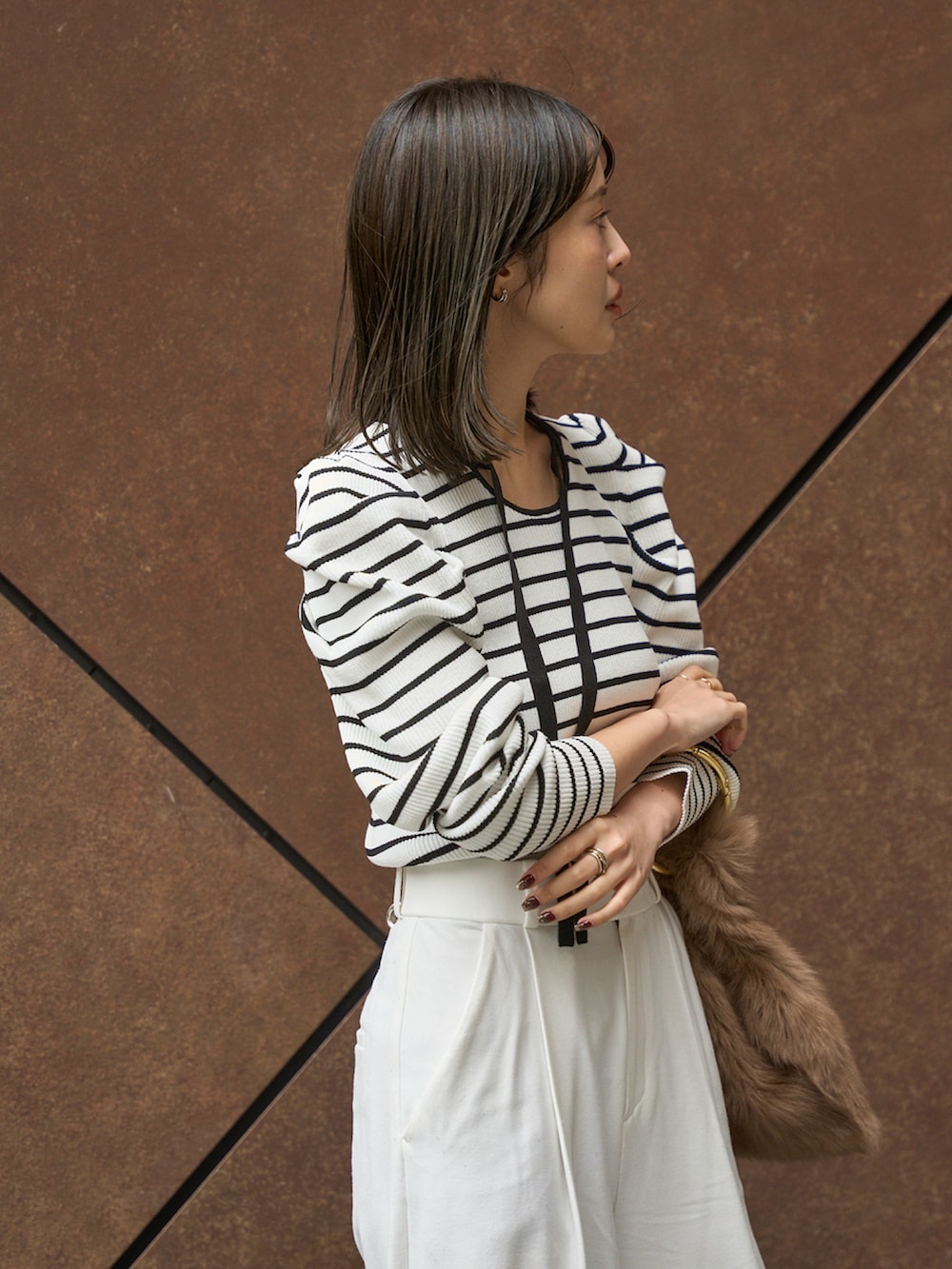 ホワイト系のニット/セーター、ベージュ系のスラックス、ブラック系のパンプスを着用したレディースの冬コーディネートの2枚目の写真