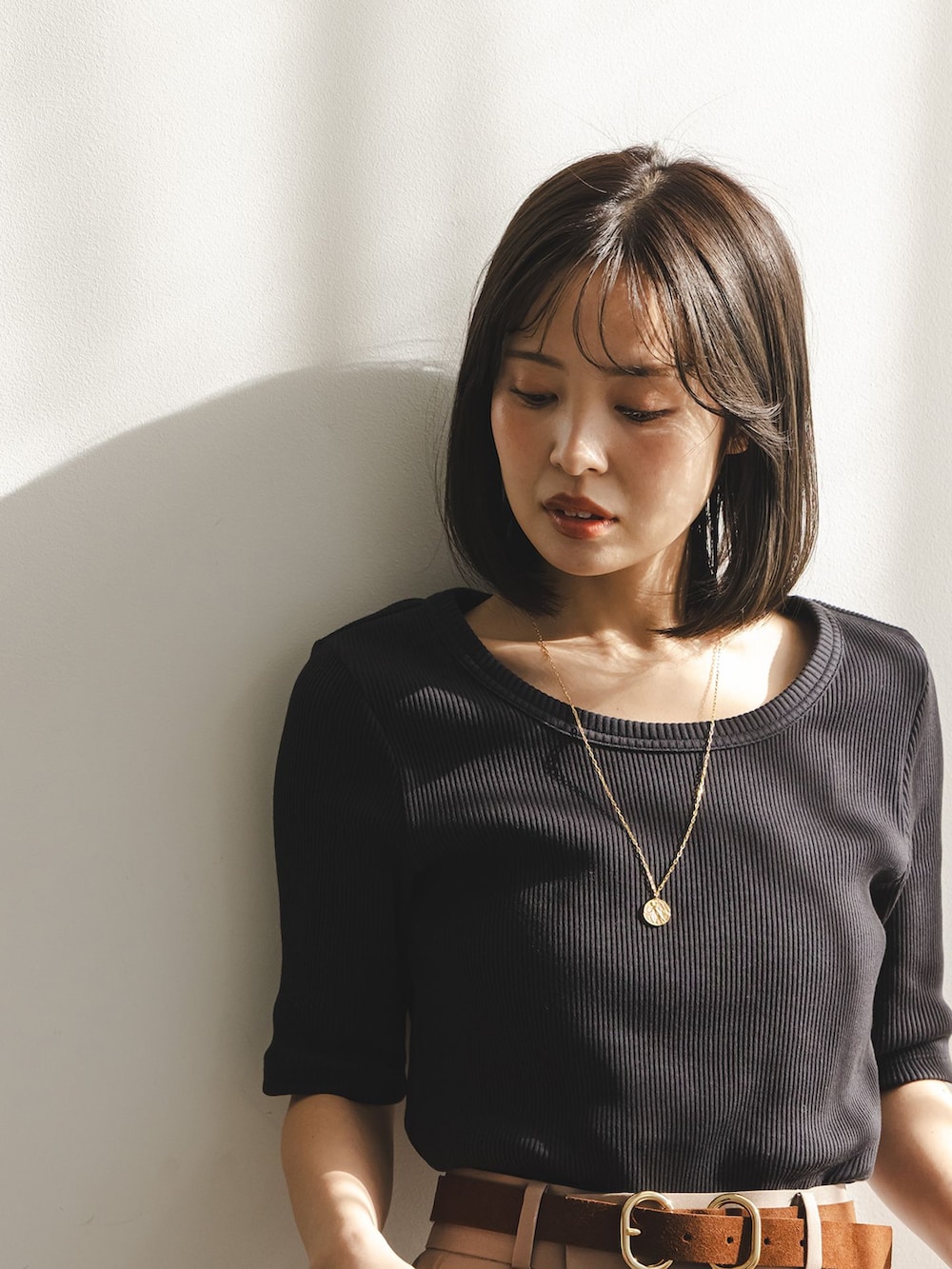 ベージュ系のスラックス、ブラック系のTシャツ/カットソー、ブラック系のボストンバッグを着用したレディースの冬コーディネートの5枚目の写真