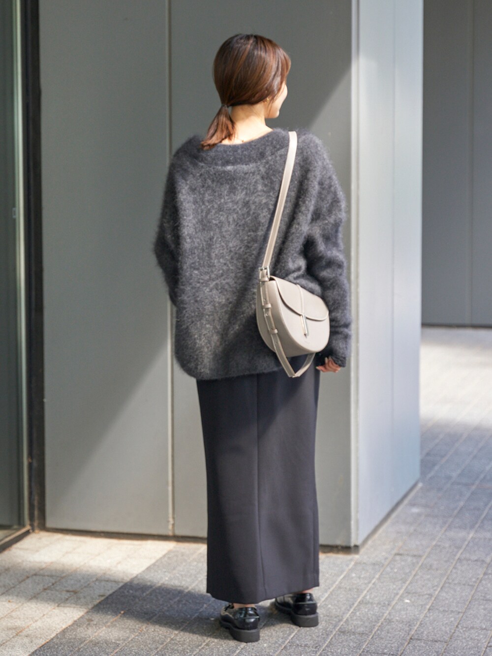 グレー系のニット/セーター、ブラック系のTシャツ/カットソー、ブラック系のスカートを着用したレディースの秋コーディネートの2枚目の写真